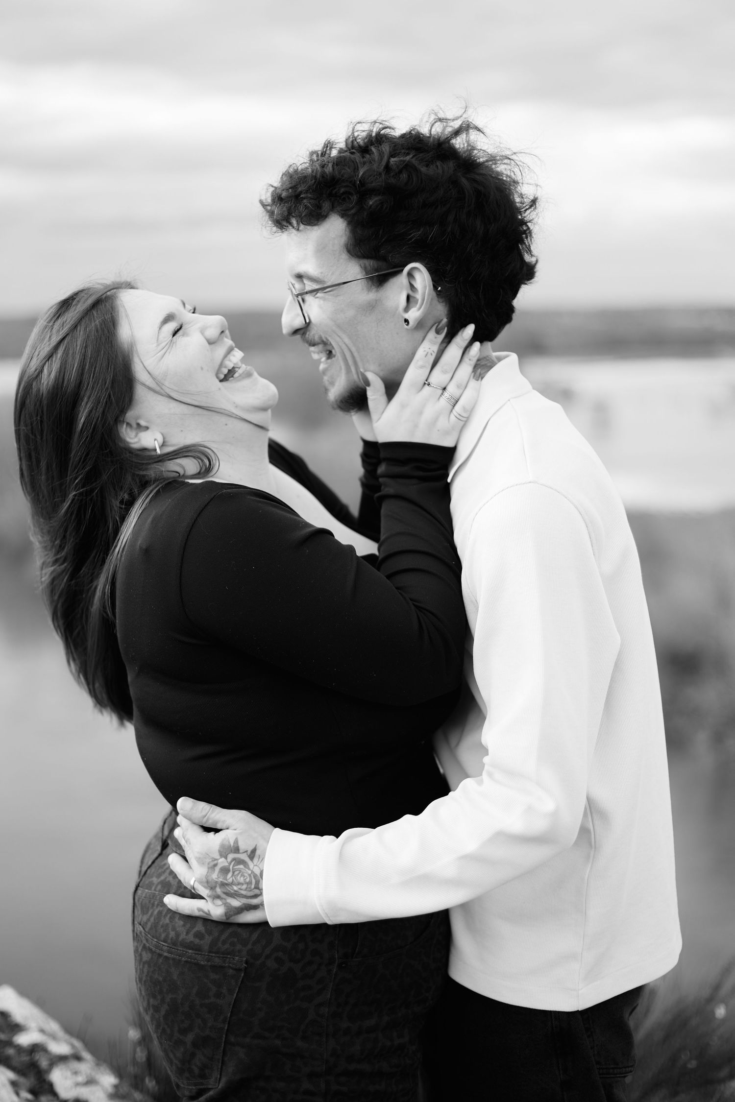 A romantic black and white photo series showing a couple embracing and laughing together outdoors.
