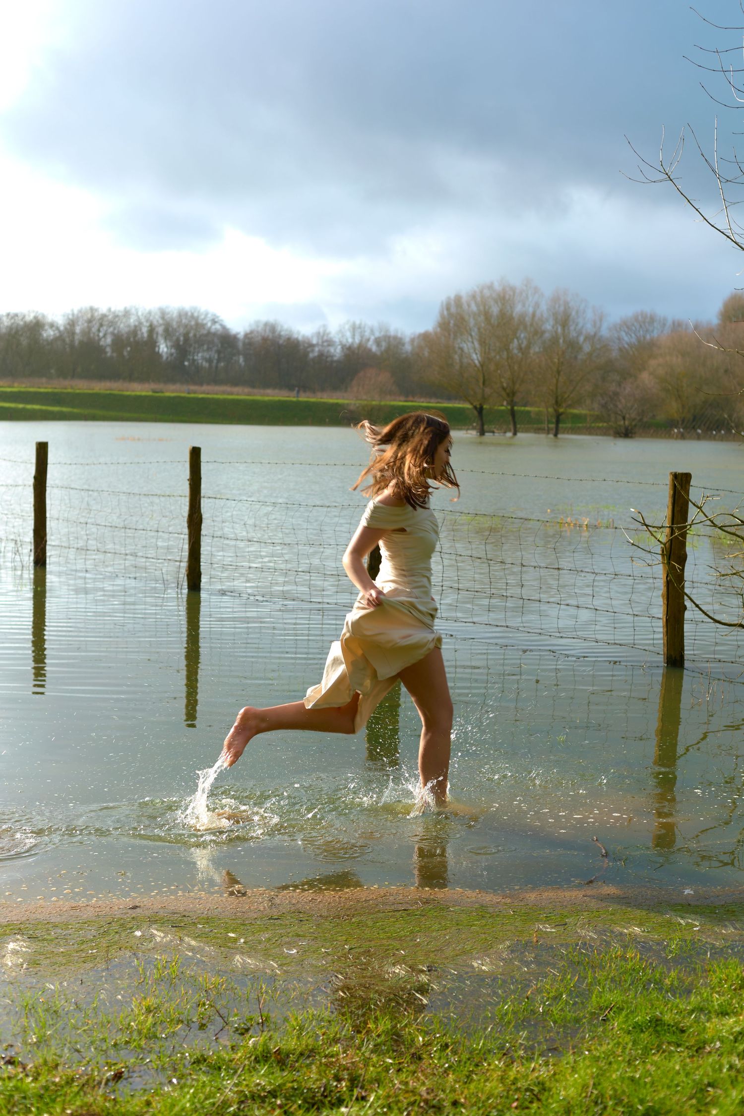 Dynamic action shot of splashing through flood water in casual white outfit.