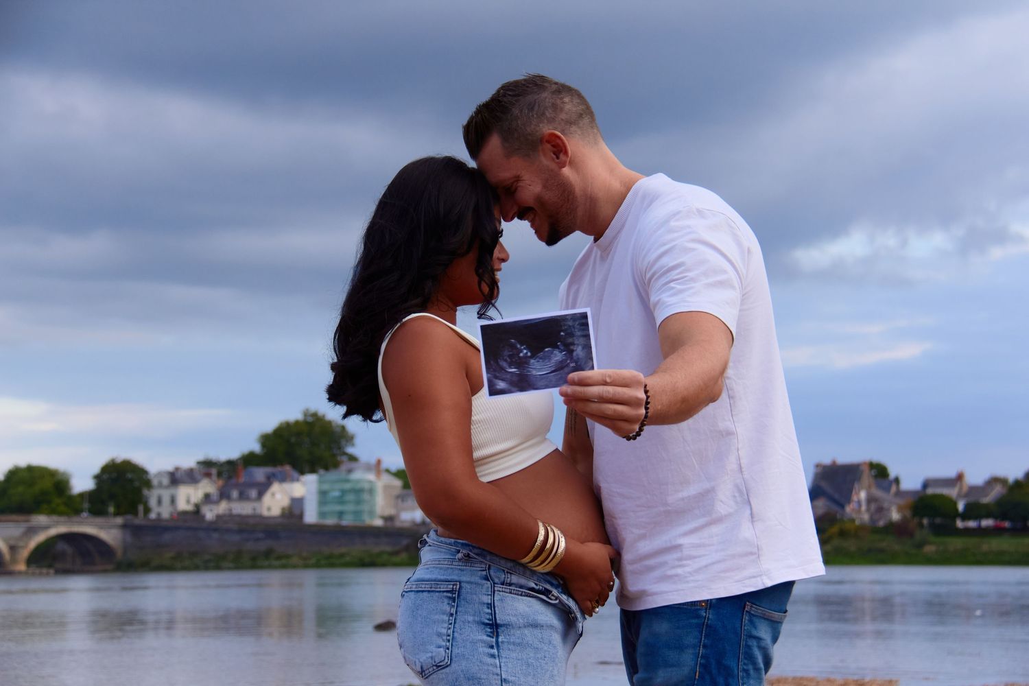 Romantic couple embracing by the waterfront during sunset.