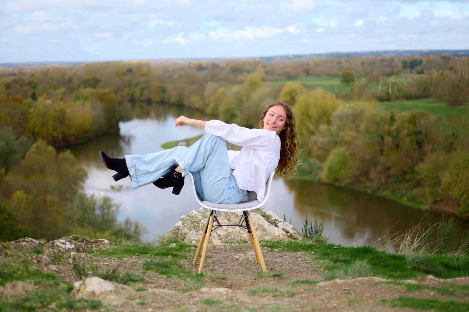 Artistic portrait session featuring a chair posed along a winding river with scenic views.