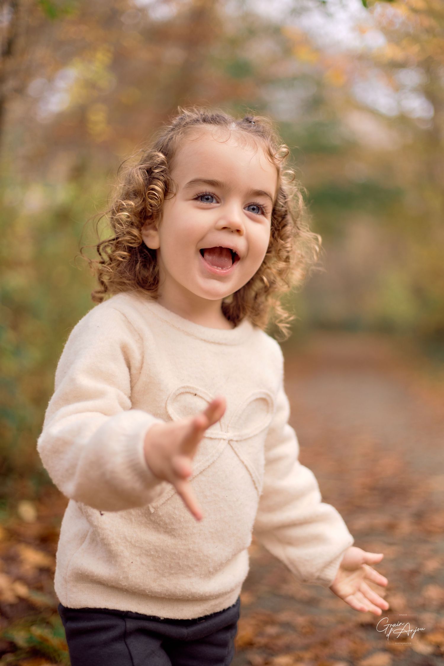 Joyful expressions captured in cream sweater against autumn foliage background.