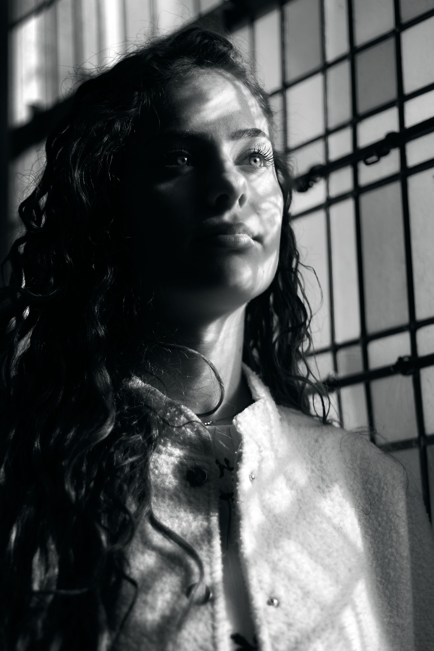 Artistic black and white portrait with dramatic shadows and window light.