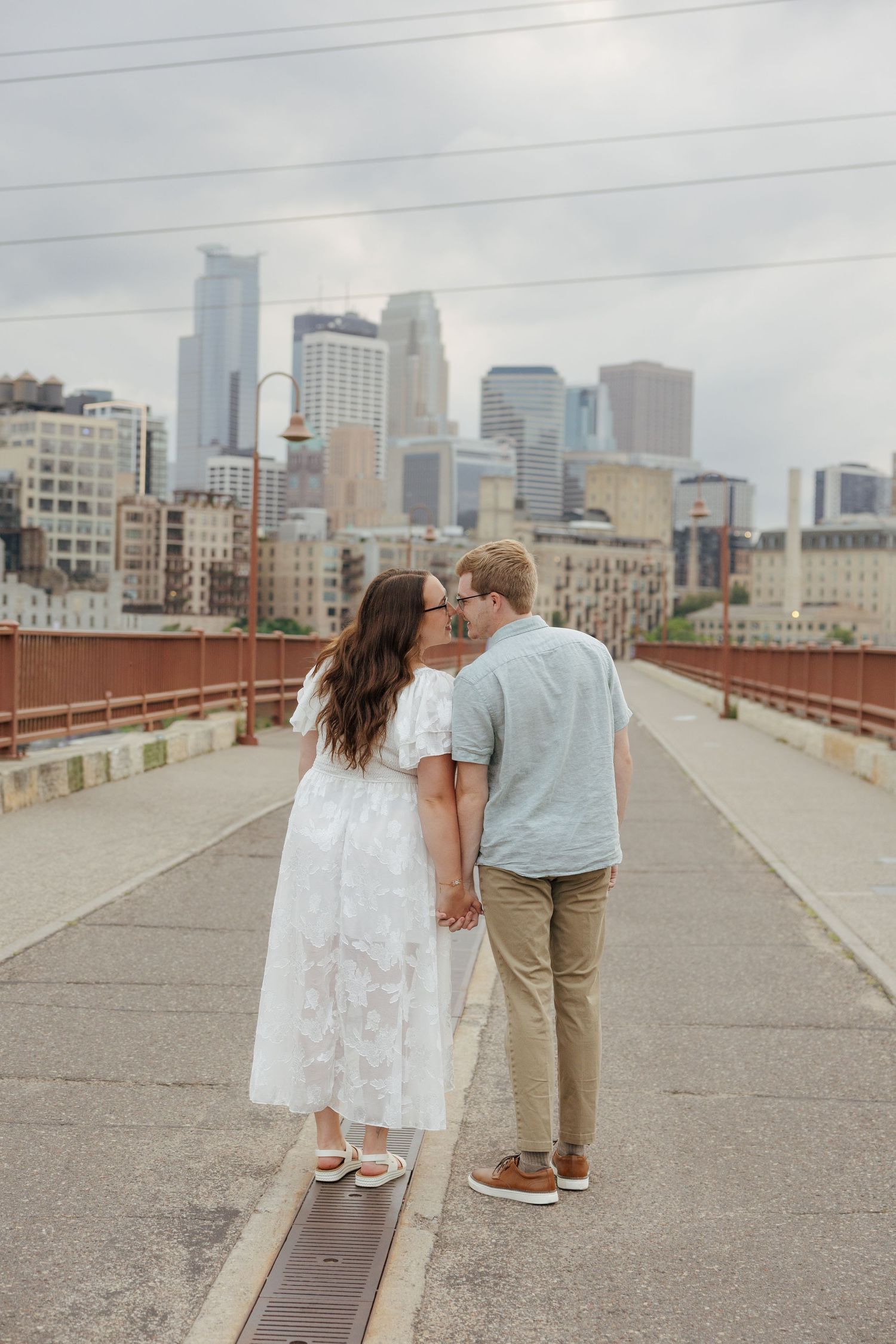 Couple sharing a kiss on a bridge with Minneapolis skyline in the background.