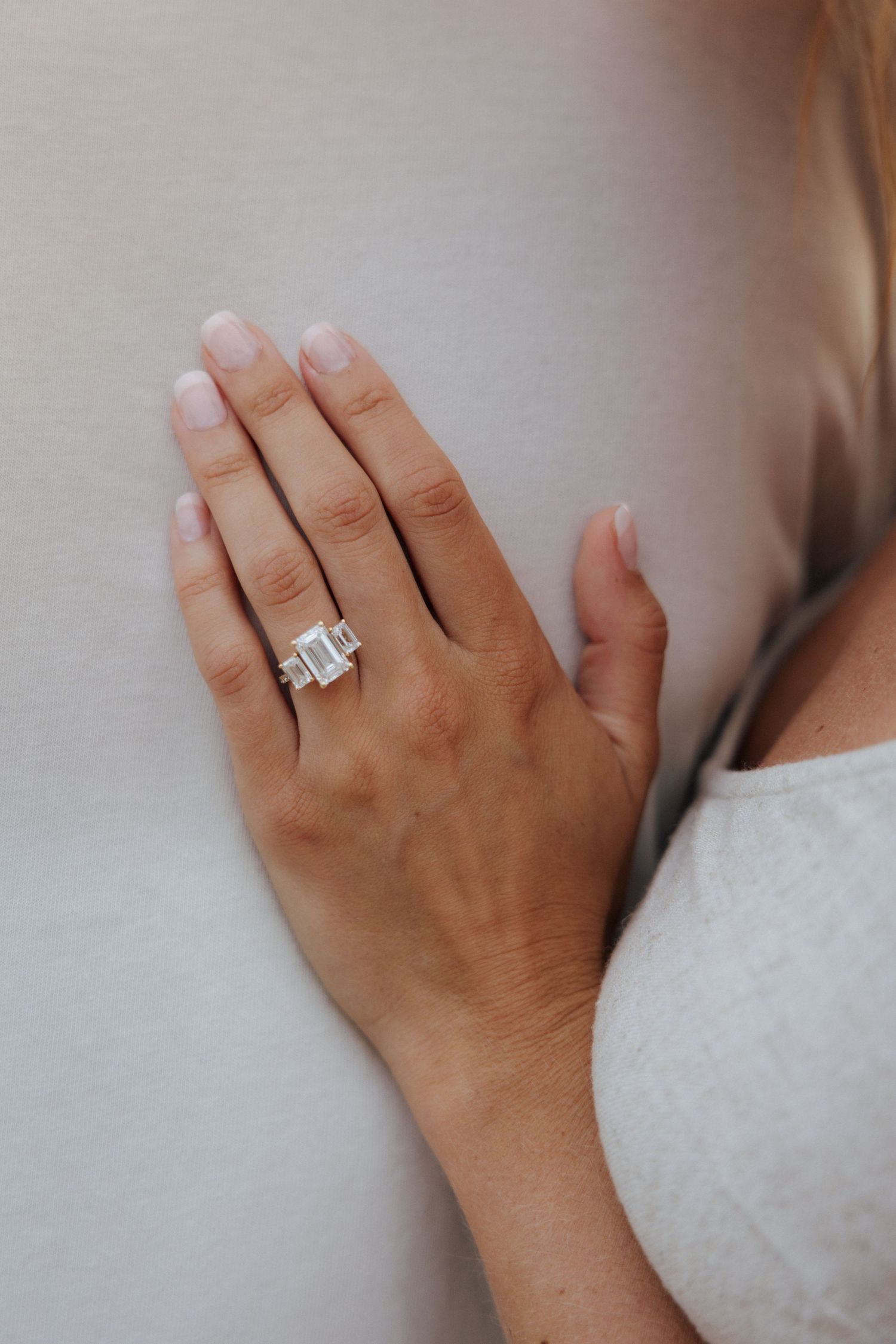 Close-up of a woman's hand displaying a stunning emerald cut diamond engagement ring.
