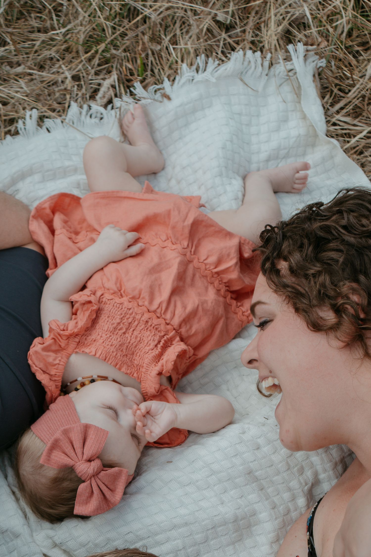 Parent leaning over newborn baby lying on a white blanket, Cochrane newborn photography