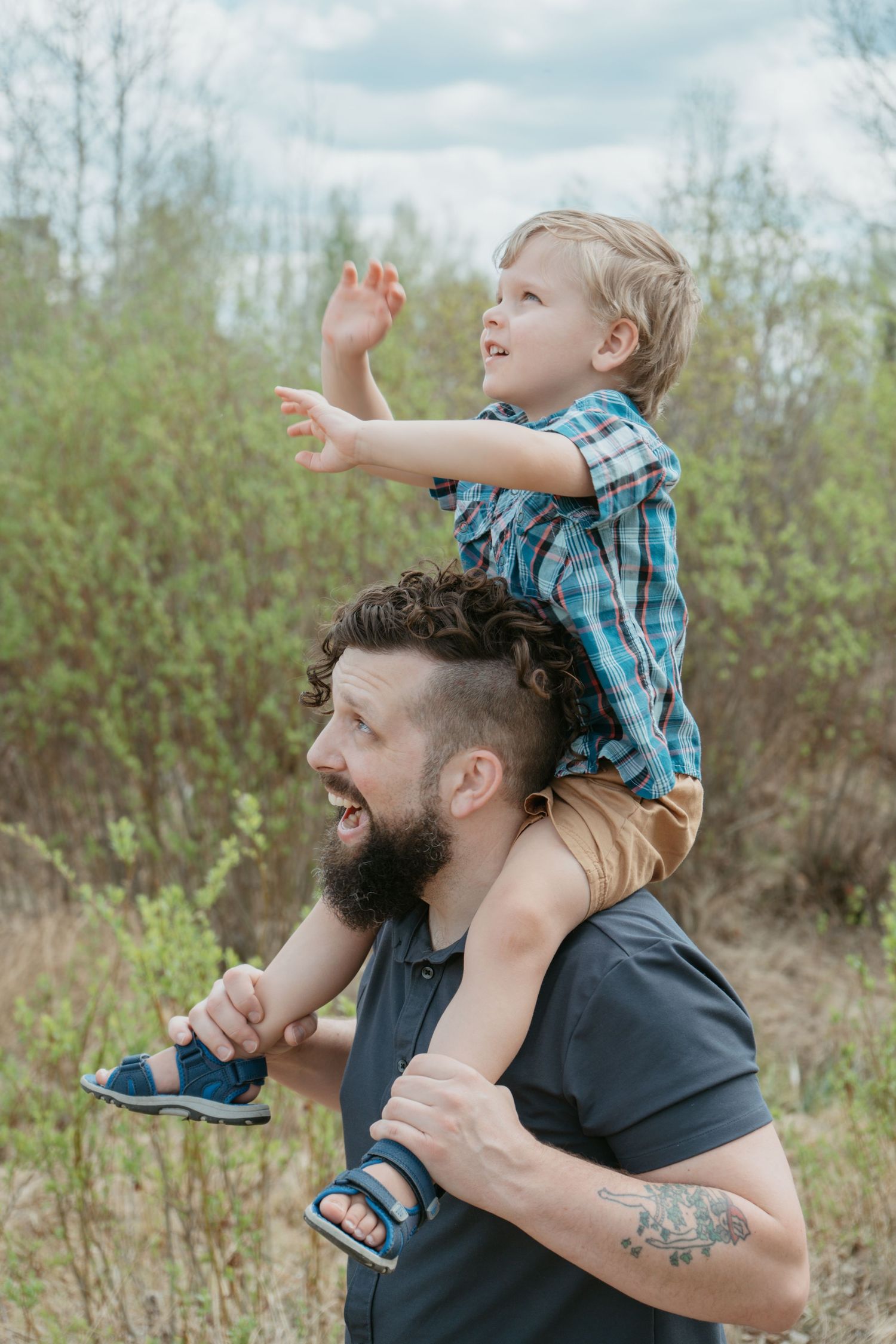 Dad lifting toddler onto his shoulders outdoors, Cochrane Alberta family portrait
