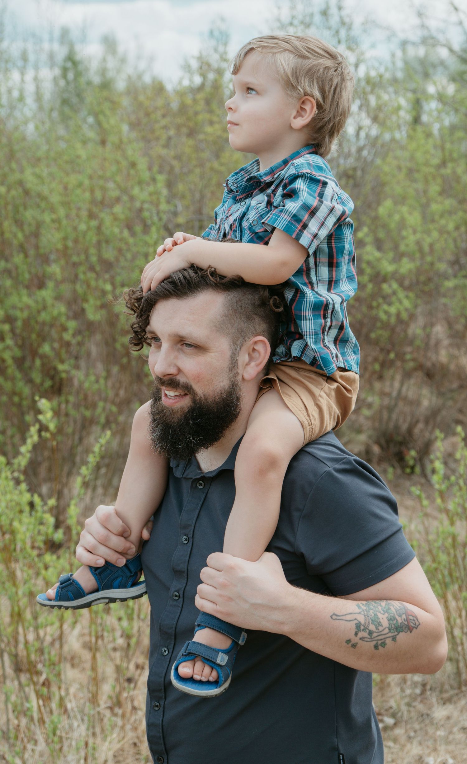 Dad lifting toddler onto his shoulders outdoors, Cochrane Alberta family portrait