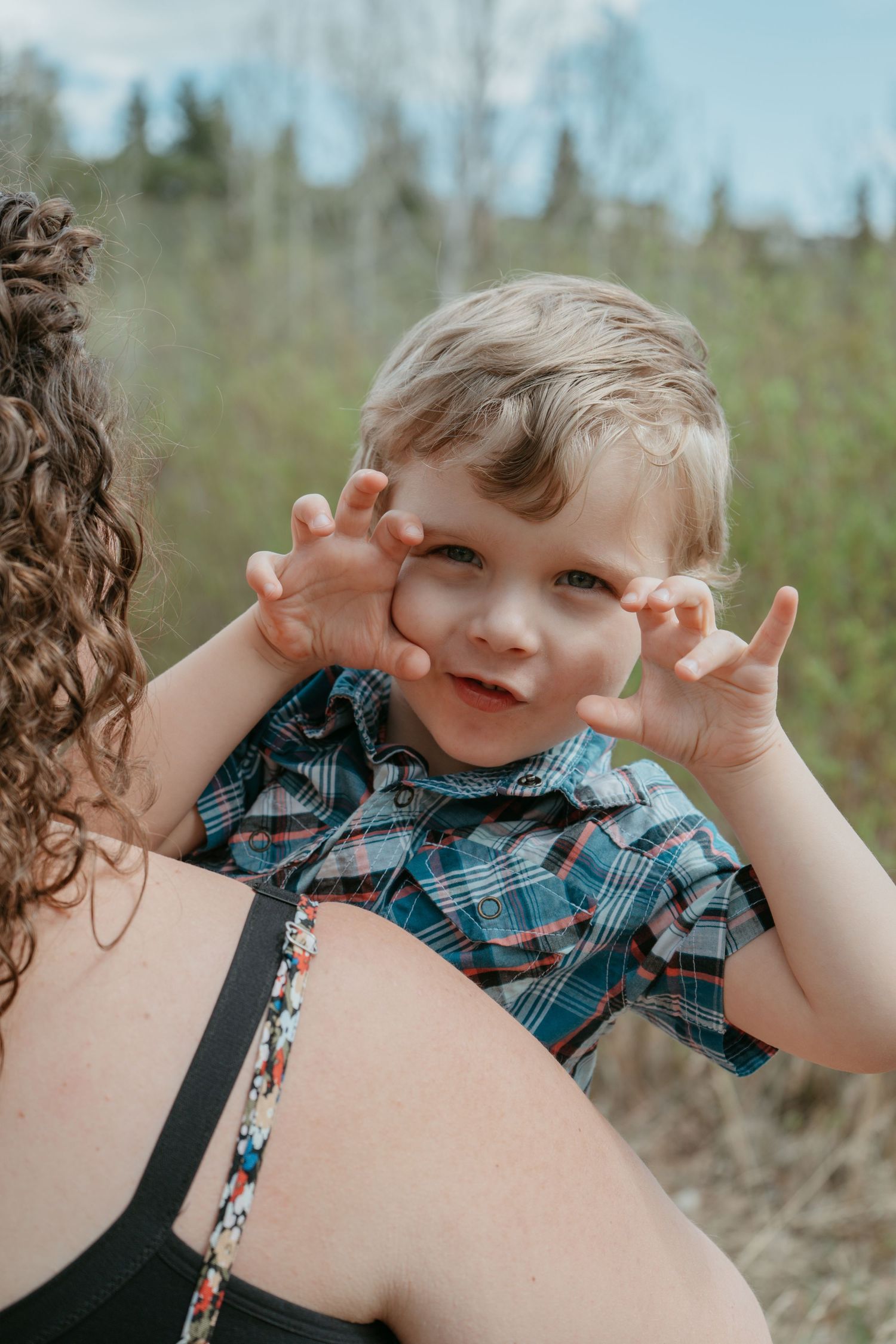 Mom holding laughing toddler boy making a silly face, Cochrane family photography
