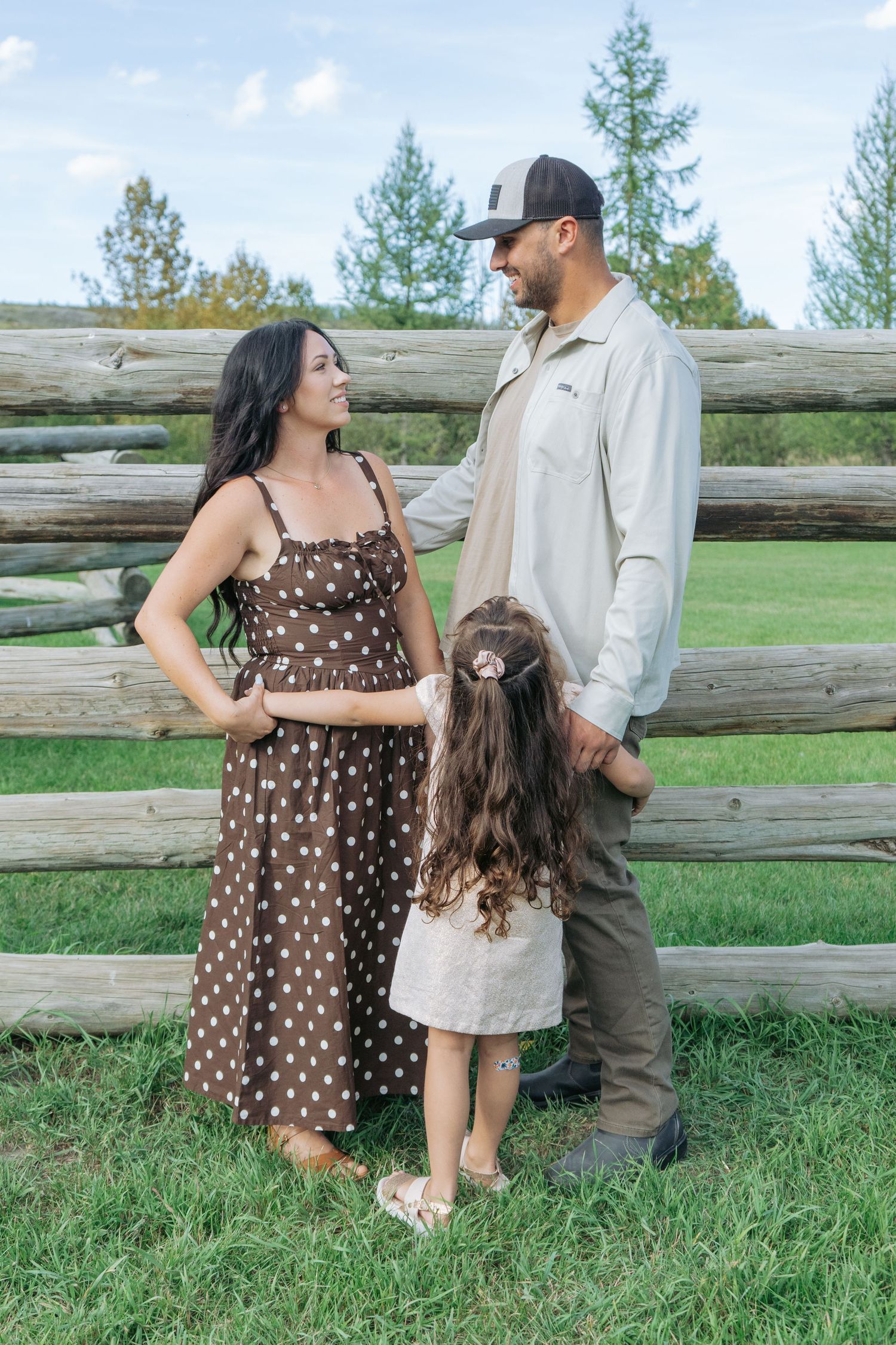 Family of four sitting together in a dry grass field, Alberta family portrait by Maddock Studios