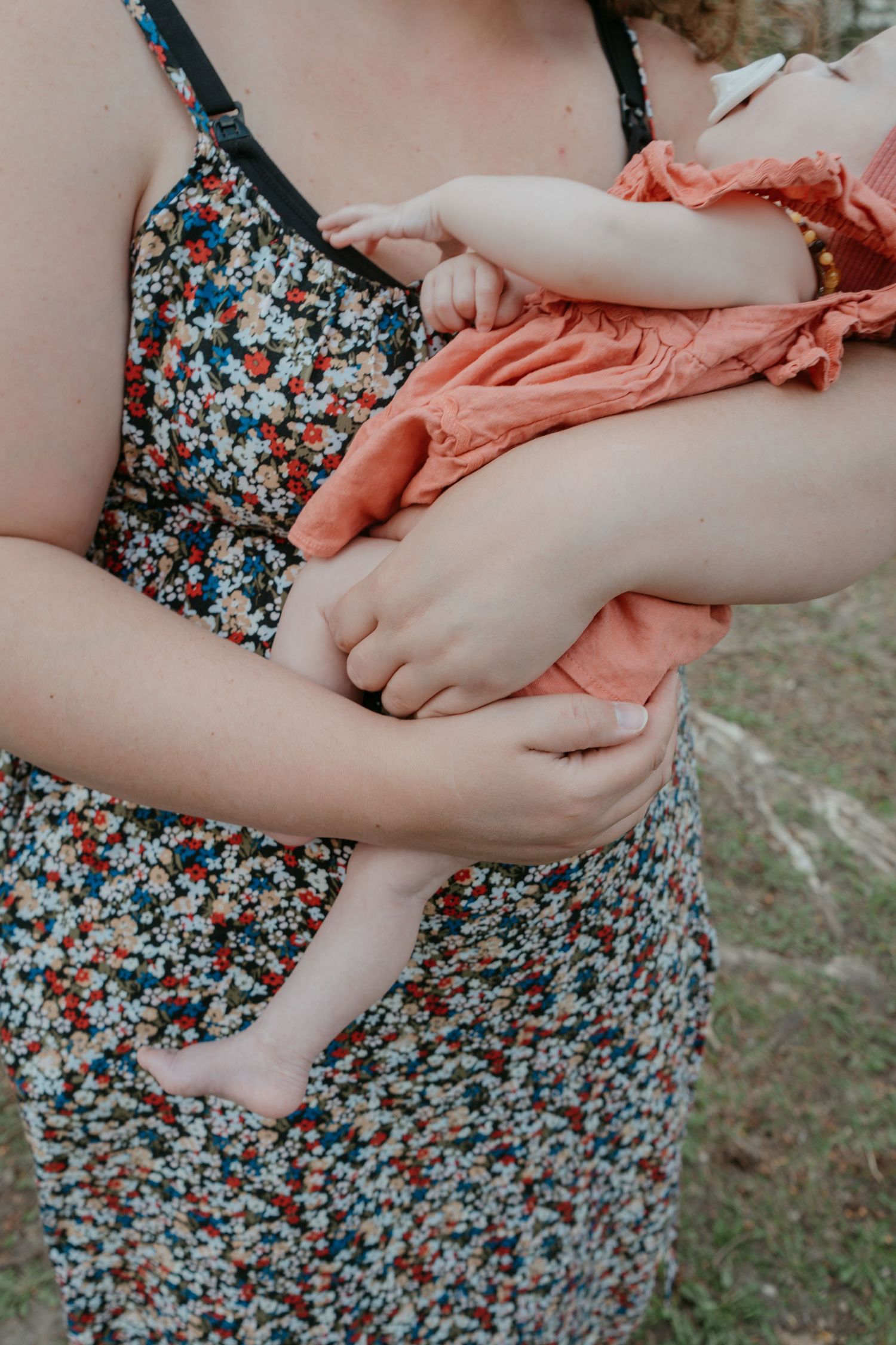 Mother cradling newborn baby in a floral dress, Cochrane newborn portrait