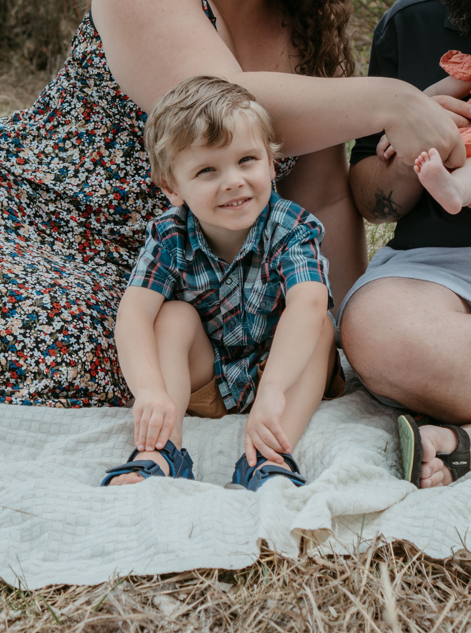 Young boy sitting on a blanket in a field looking up, candid Cochrane family photography