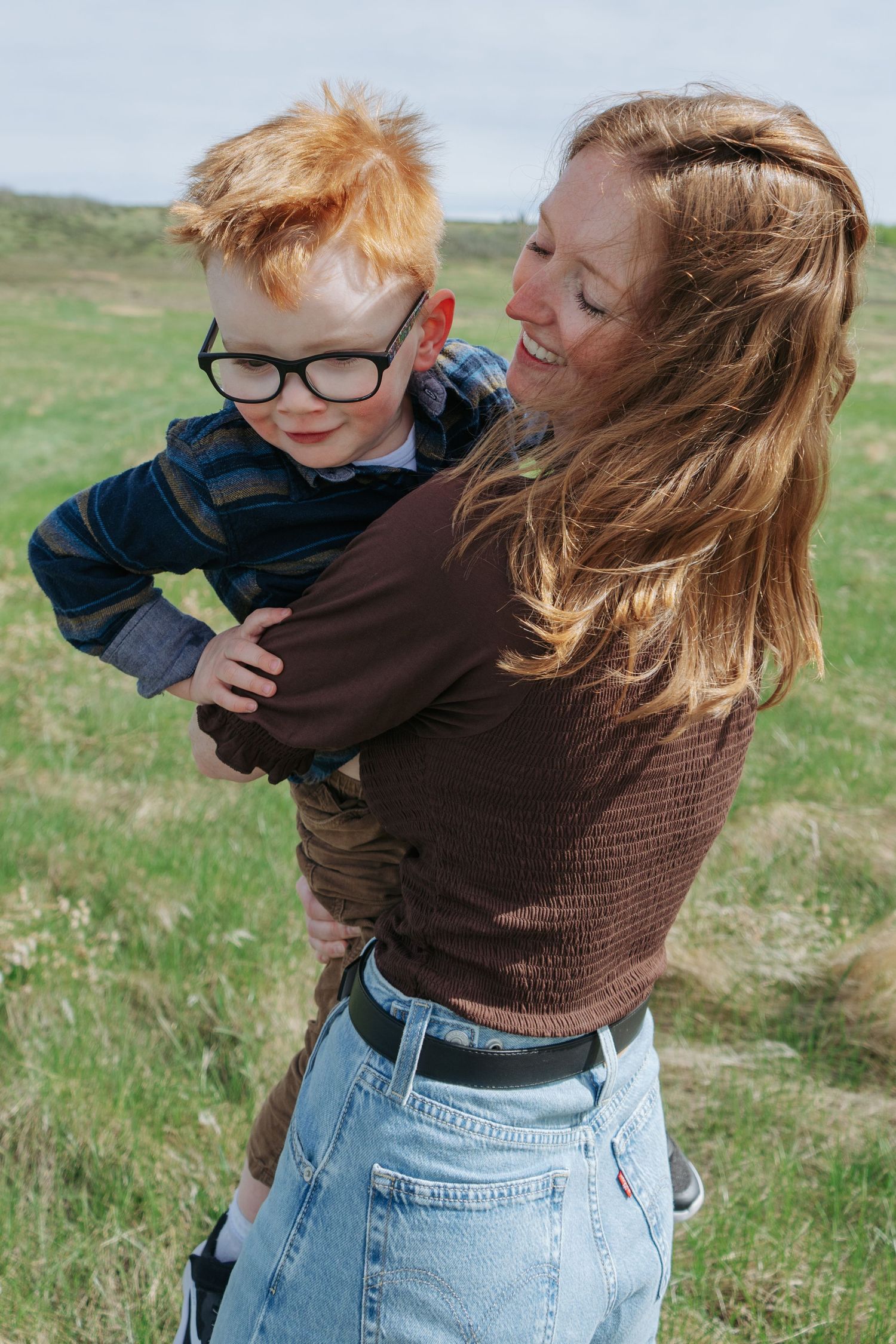 Mom and red-haired boy laughing together outdoors, Cochrane family photography