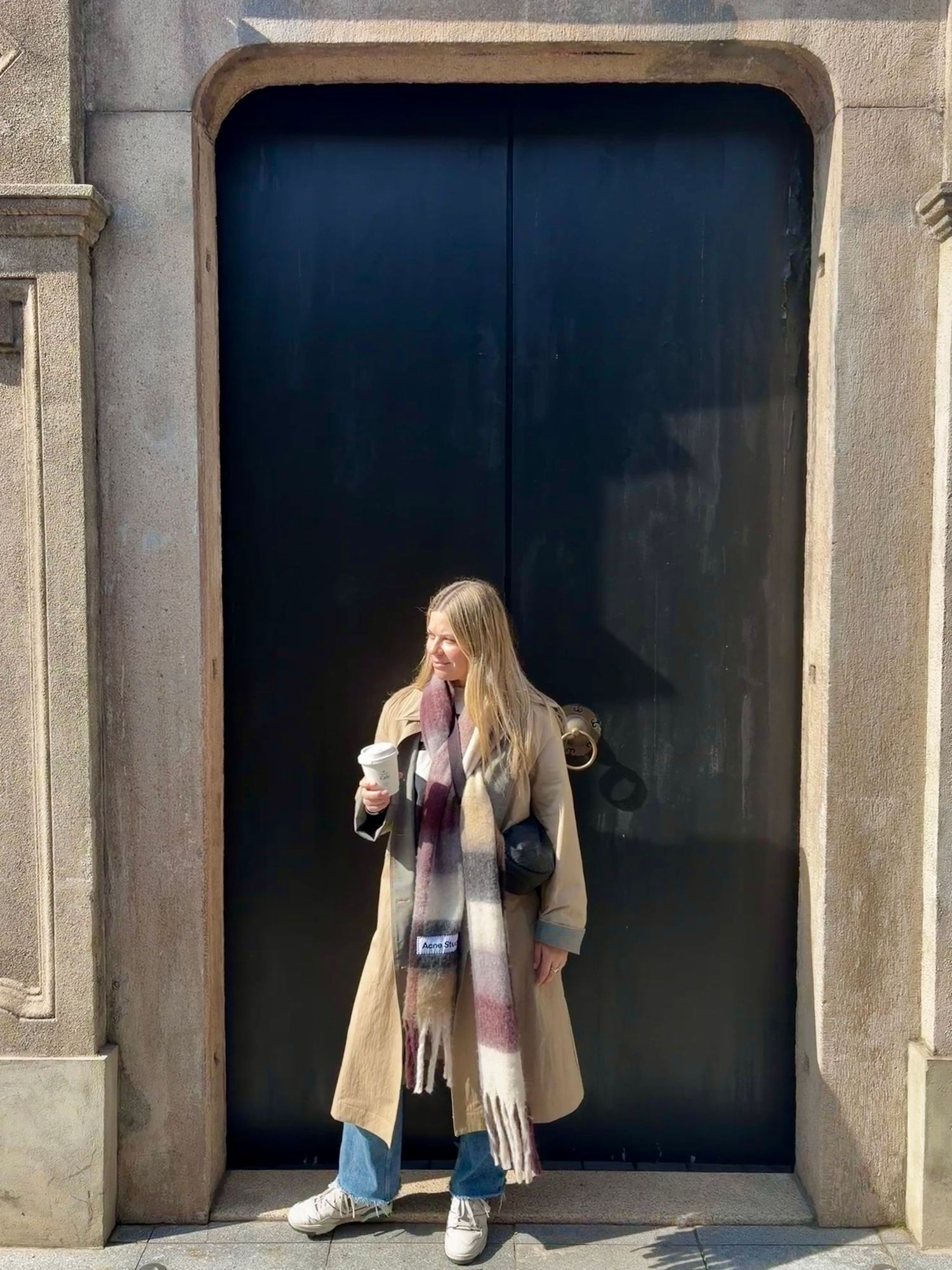 Woman standing in front of a large dark doorway, lifestyle portrait by Maddock Studios