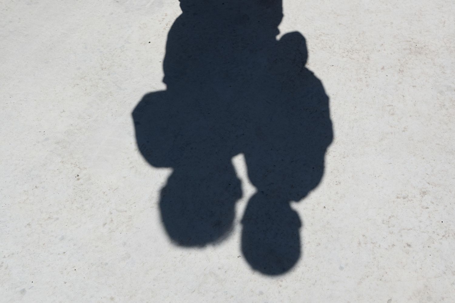 Shadow of a parent and toddler cast on a concrete surface, creative family photography