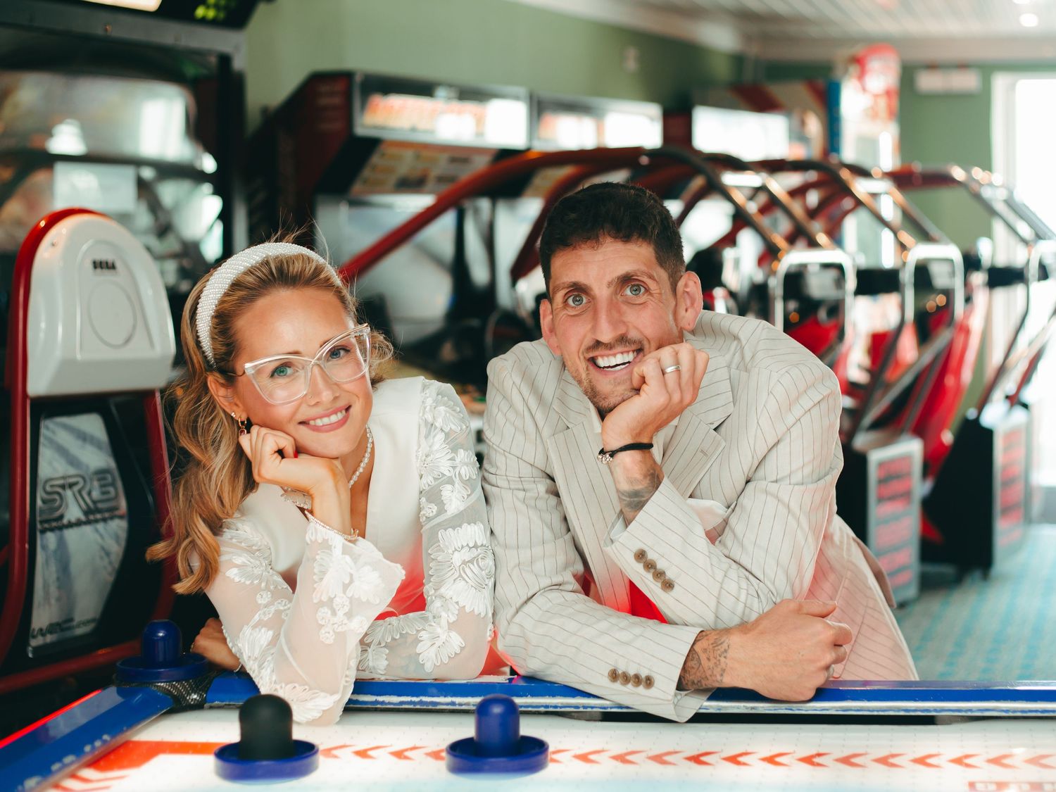 Wedding couple leaning on air hockey table in colorful arcade, in Brighton