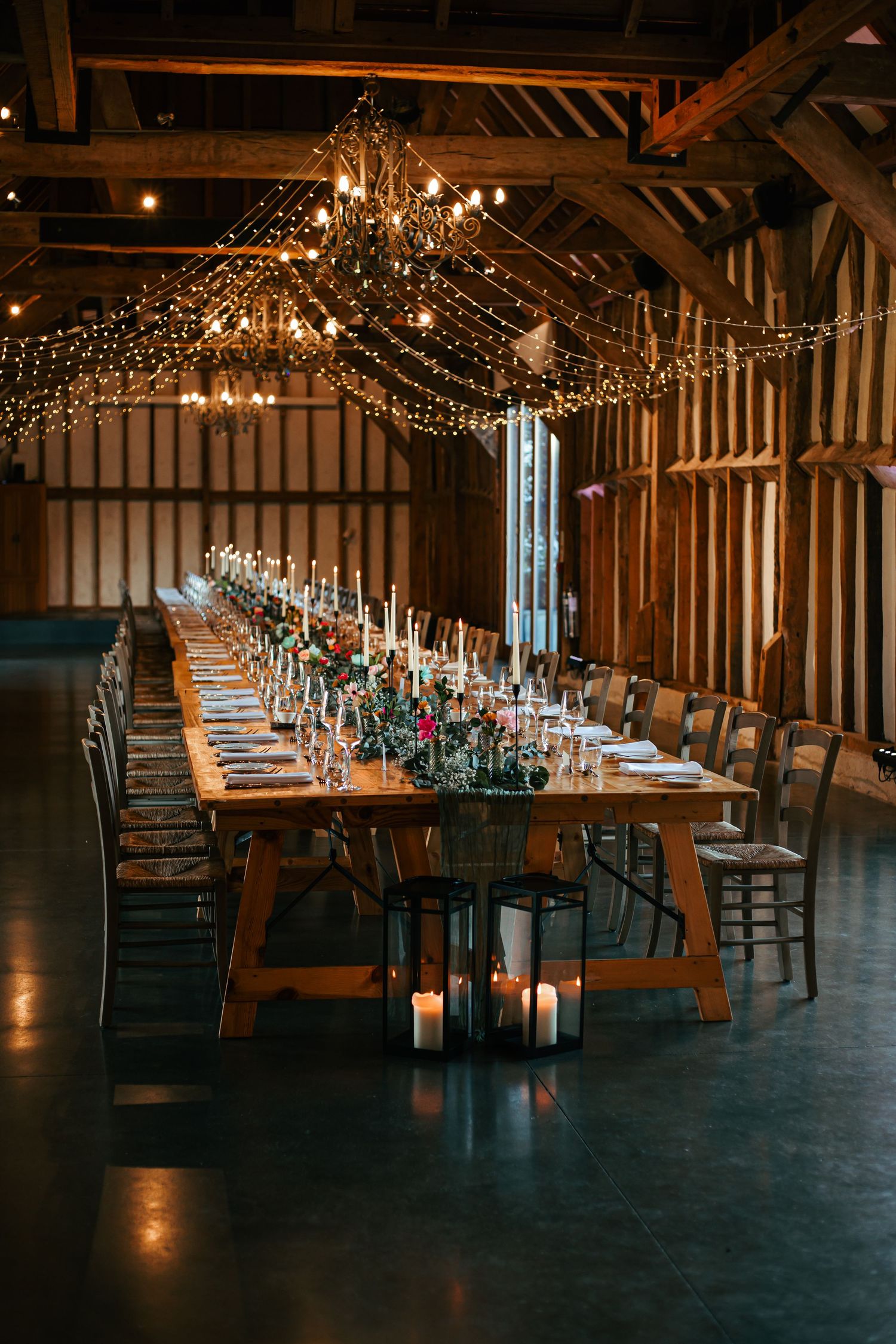Reception tables decorated with string lights and place settings create an elegant wedding atmosphere at Southend Barns near Chichester