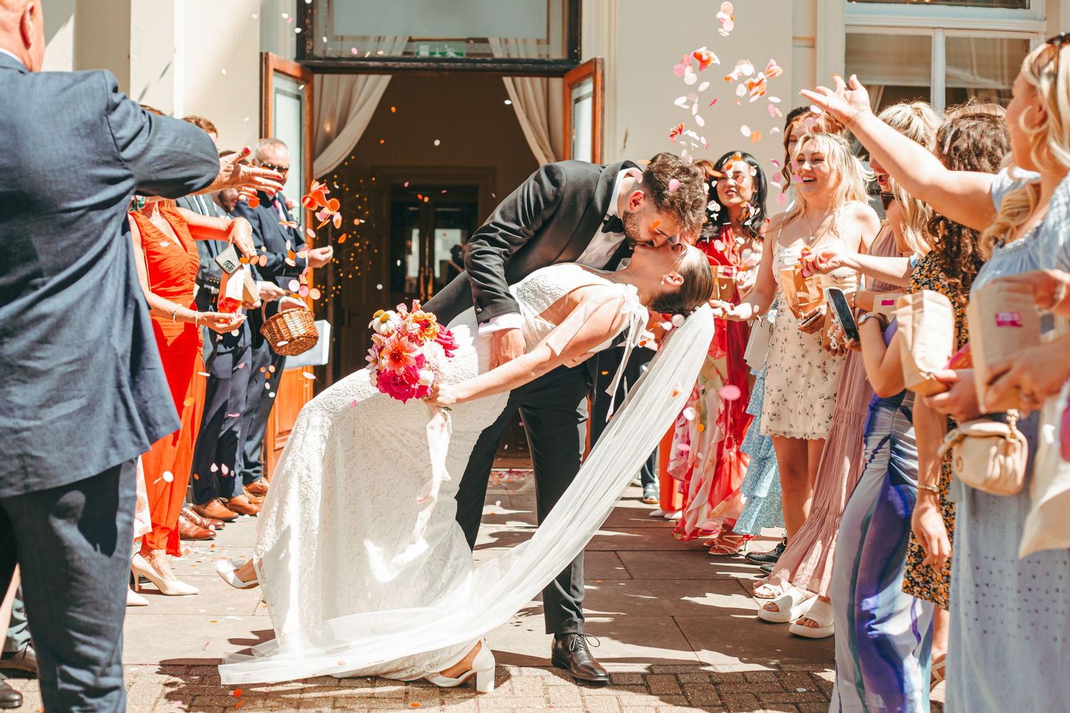 A wedding couple celebrate with a dip kiss outside Brighton Town Hall during their confetti moment