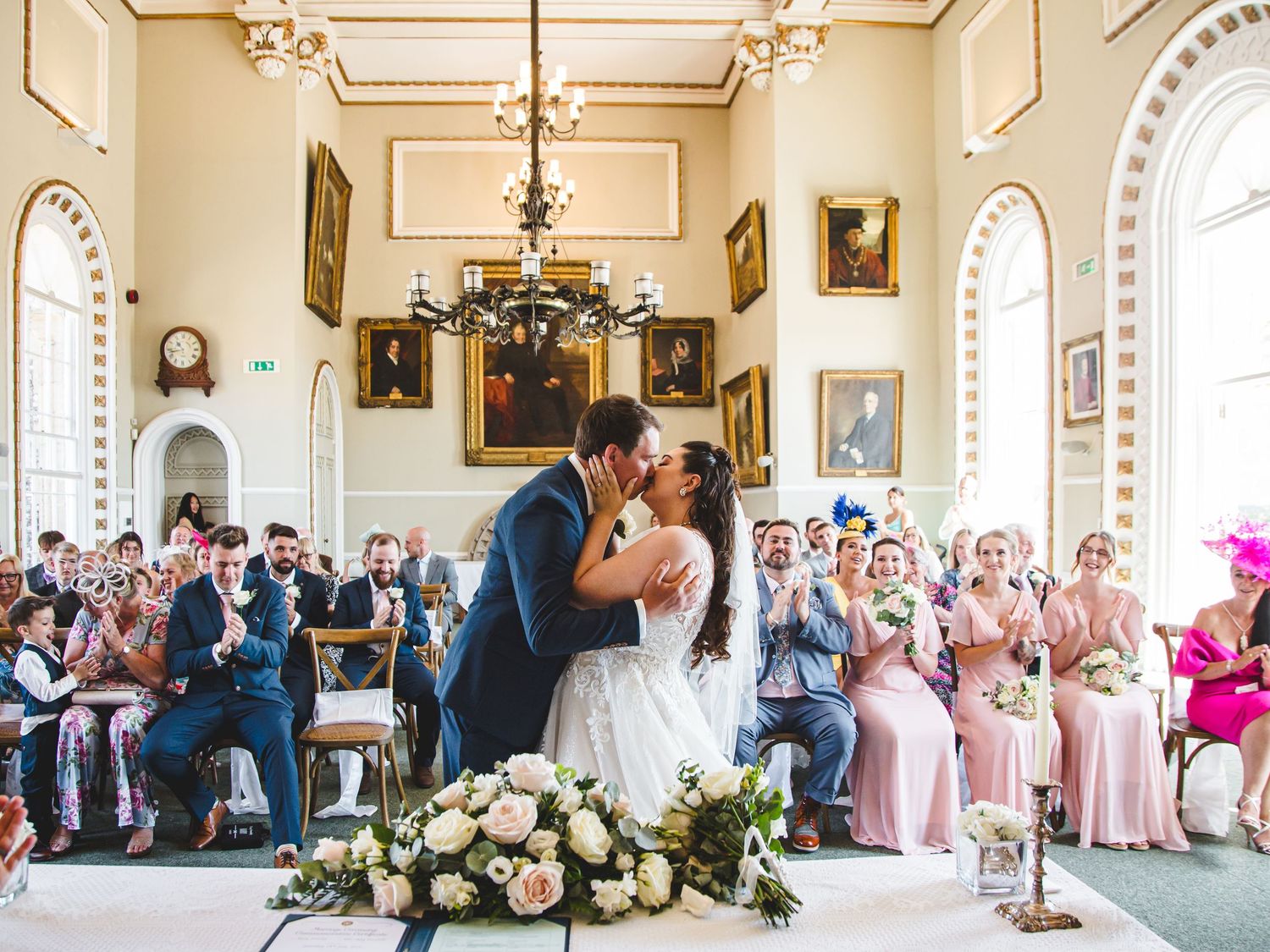 Newlyweds share their first kiss during an elegant ceremony in the grand historic room within Arundel Town Hall, West Sussex.
