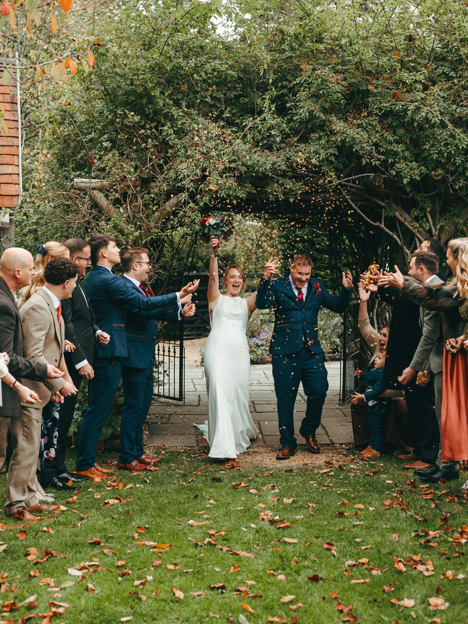 newlyweds confetti line on the lawn surrounded by Autumn foliage at Rumbold Farm.