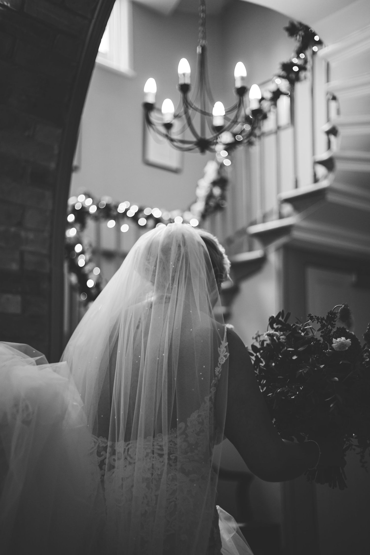 A black and white wedding photo series showing a bride's veil in soft focus with elegant chandeliers in the background.