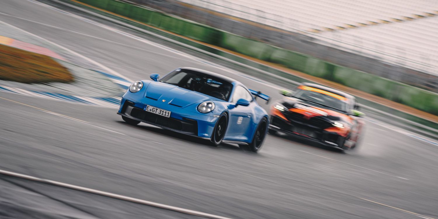 Performance vehicles racing around a curved section of a professional racing circuit.