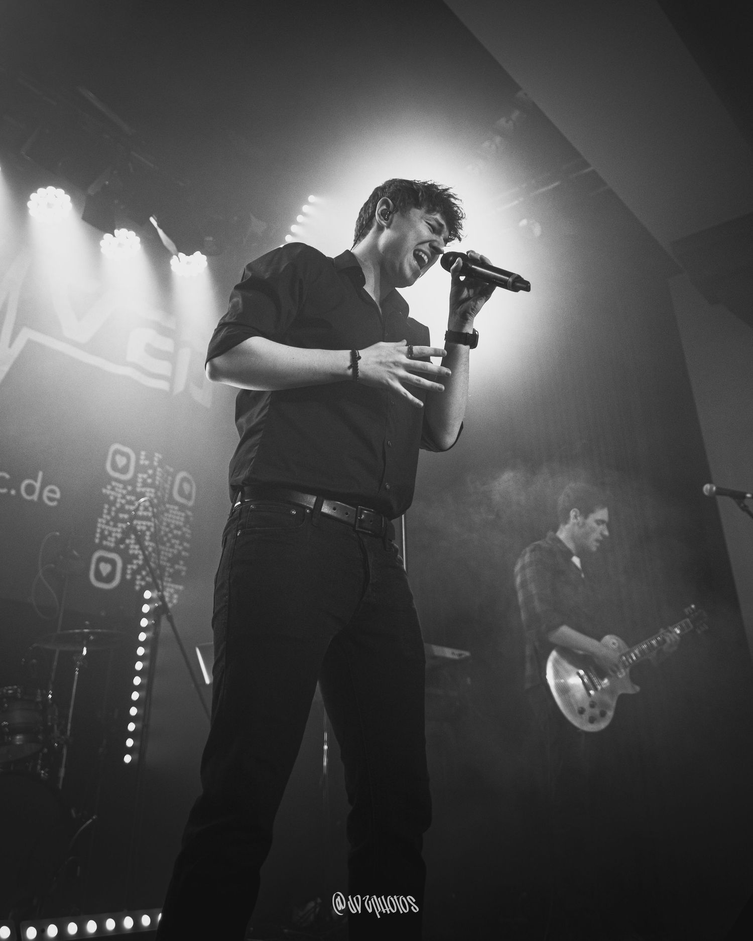 Black and white concert photography showing performers on stage with dramatic lighting.