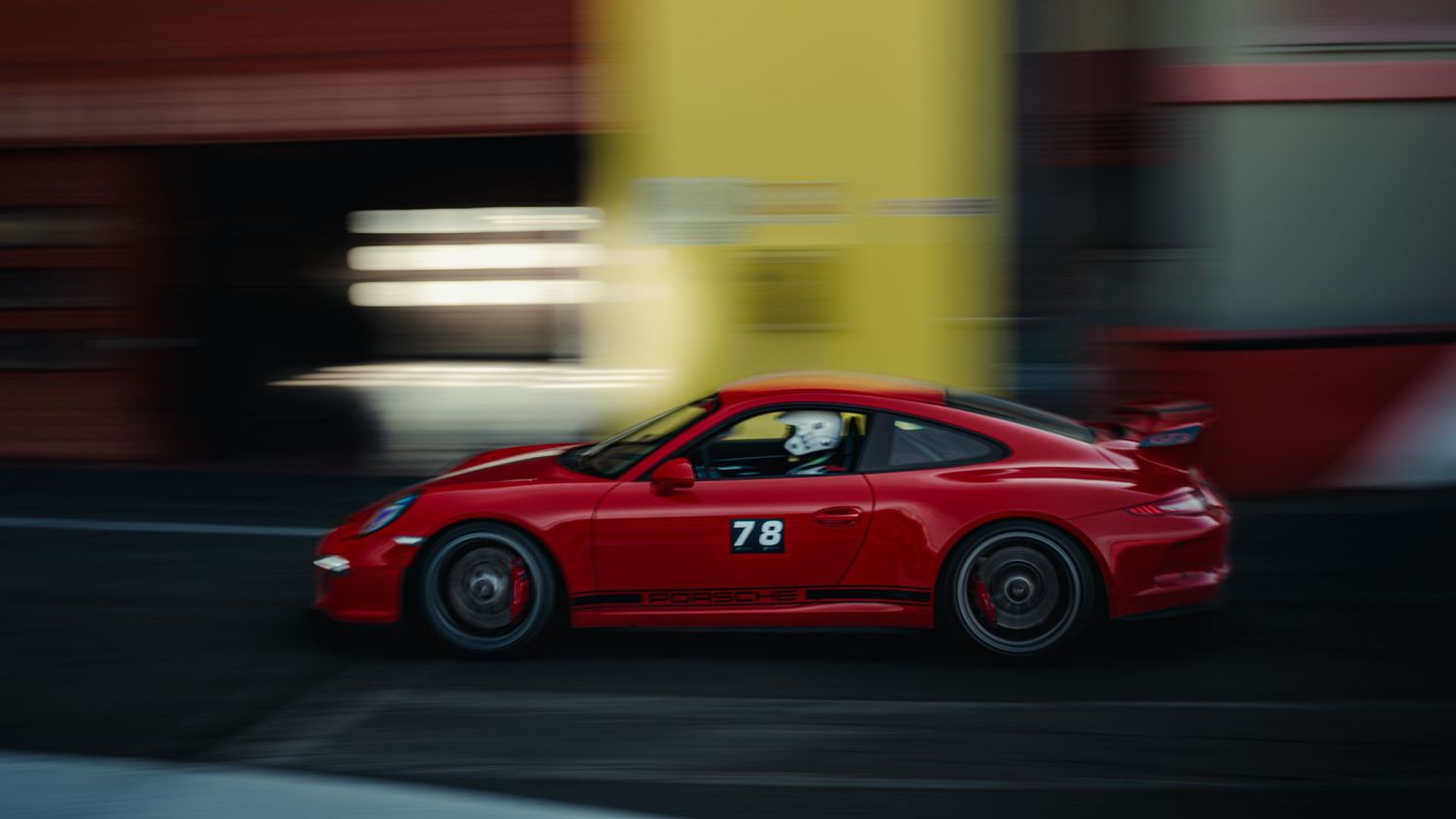 Red Porsche 911 GT3 number 78 racing on track with motion blur.