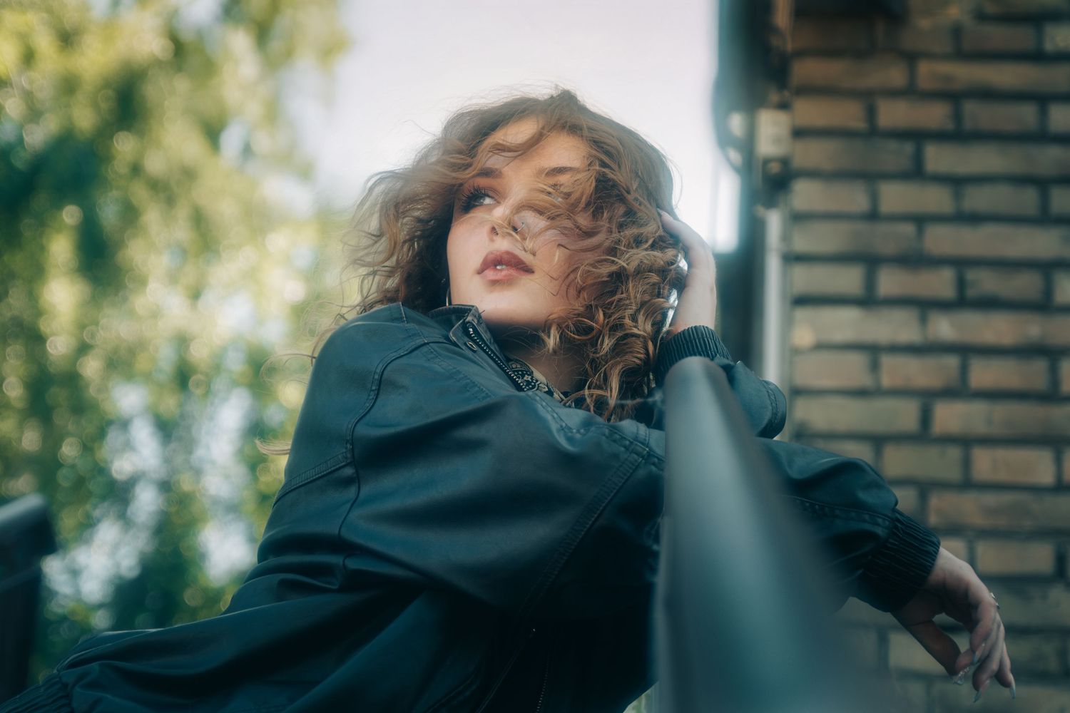Artistic portrait series showing dramatic poses against a brick wall with moody lighting.