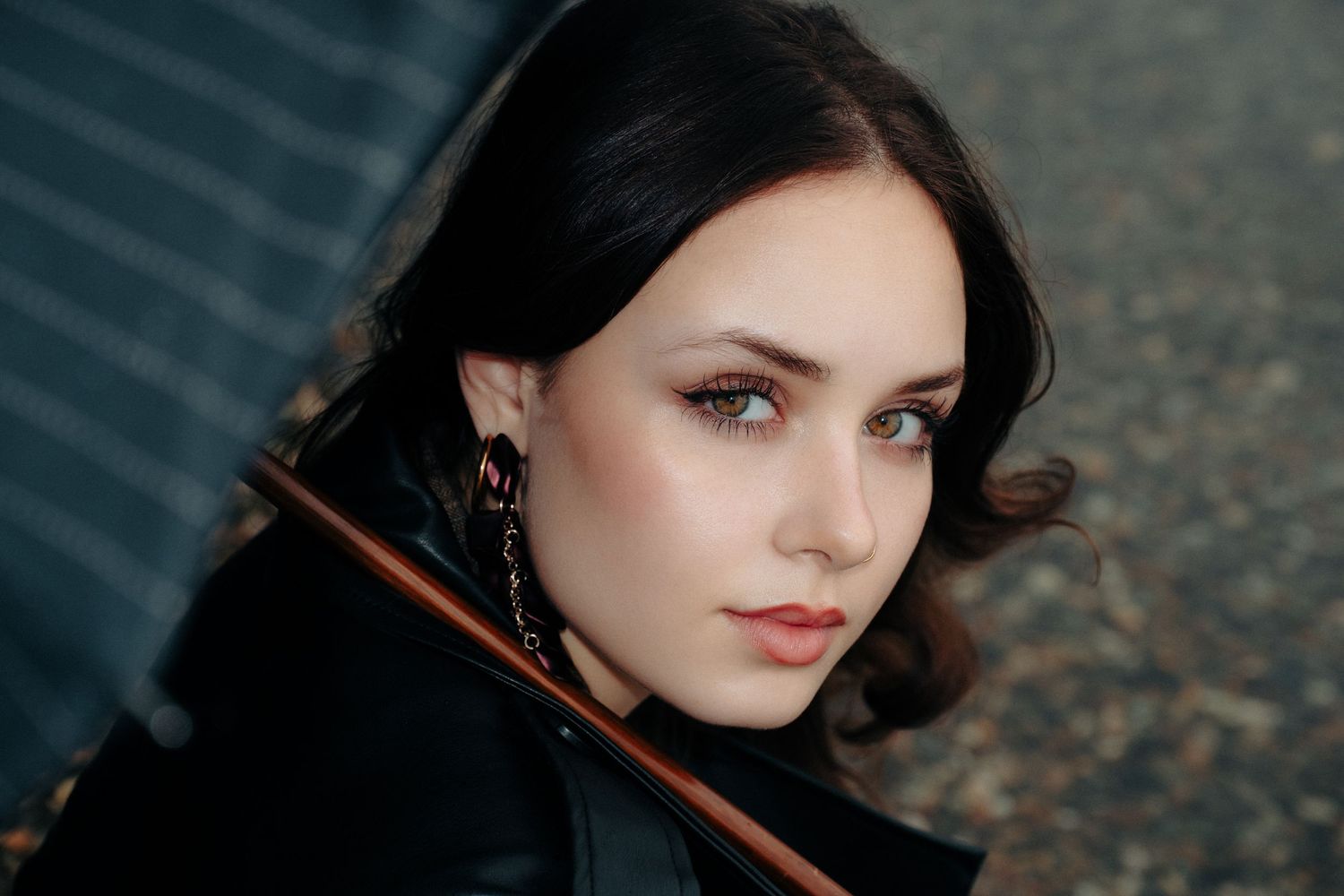 Dramatic close-up portrait with black coat and delicate jewelry.
