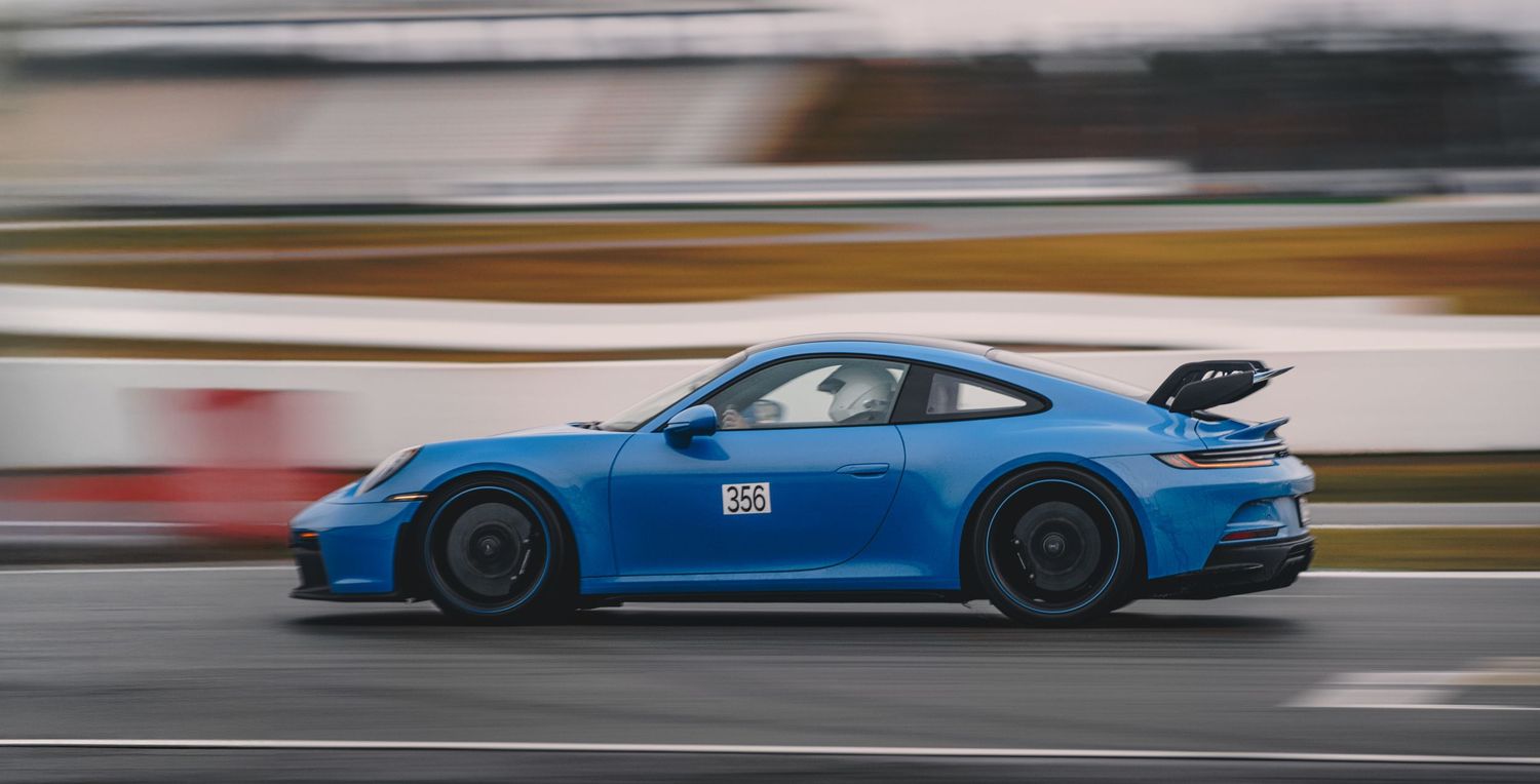 Blue racing cars speeding along a professional race track with motion blur.