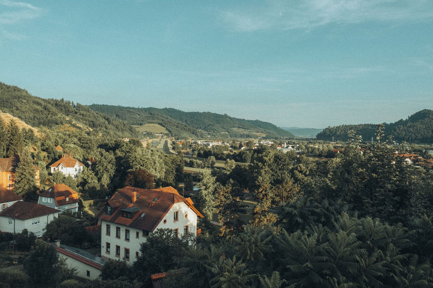 Panoramic view of hillside houses and buildings under blue sky in a Mediterranean setting.