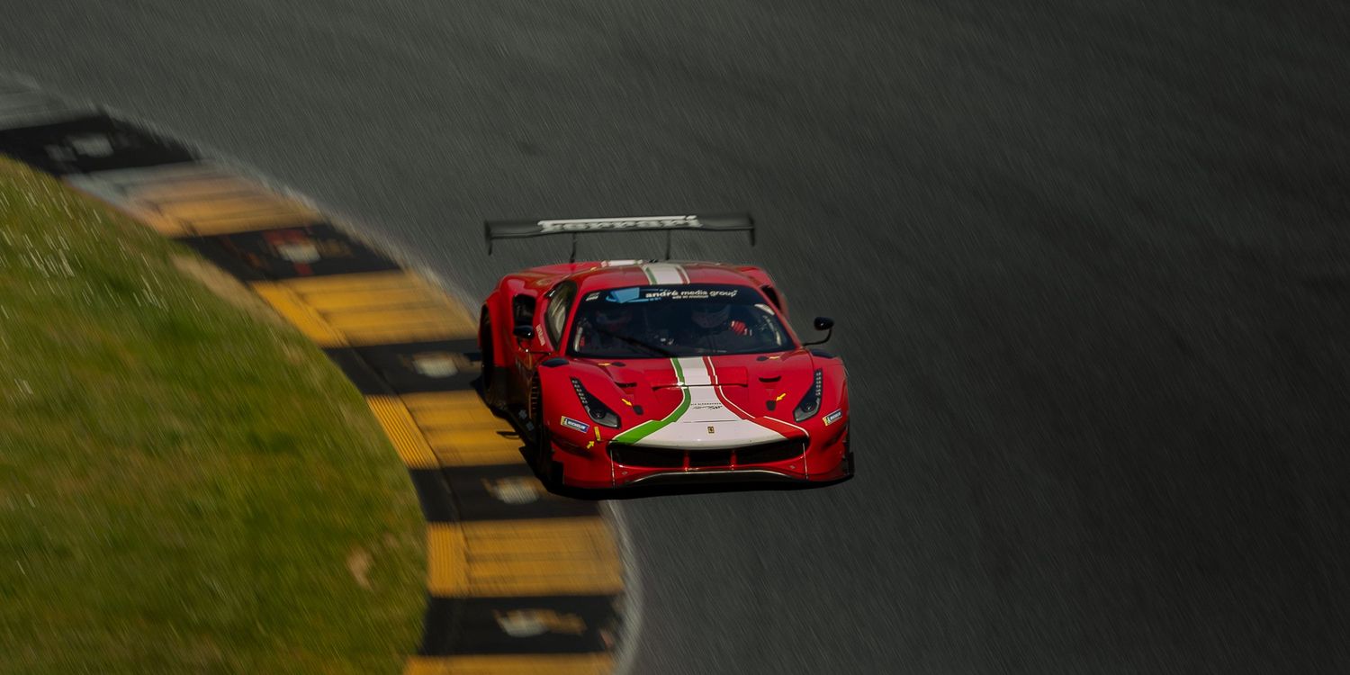 Red Ferrari 488 GT3 racing car navigating a curved track during a motorsport competition.
