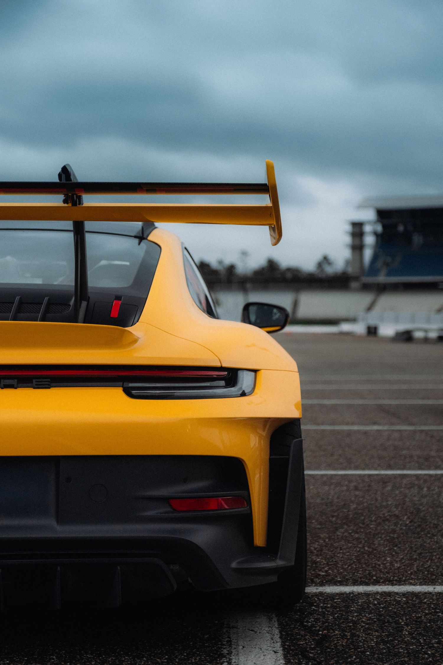 Close-up shots of a yellow Porsche GT3 RS rear wing and body details on a race track.