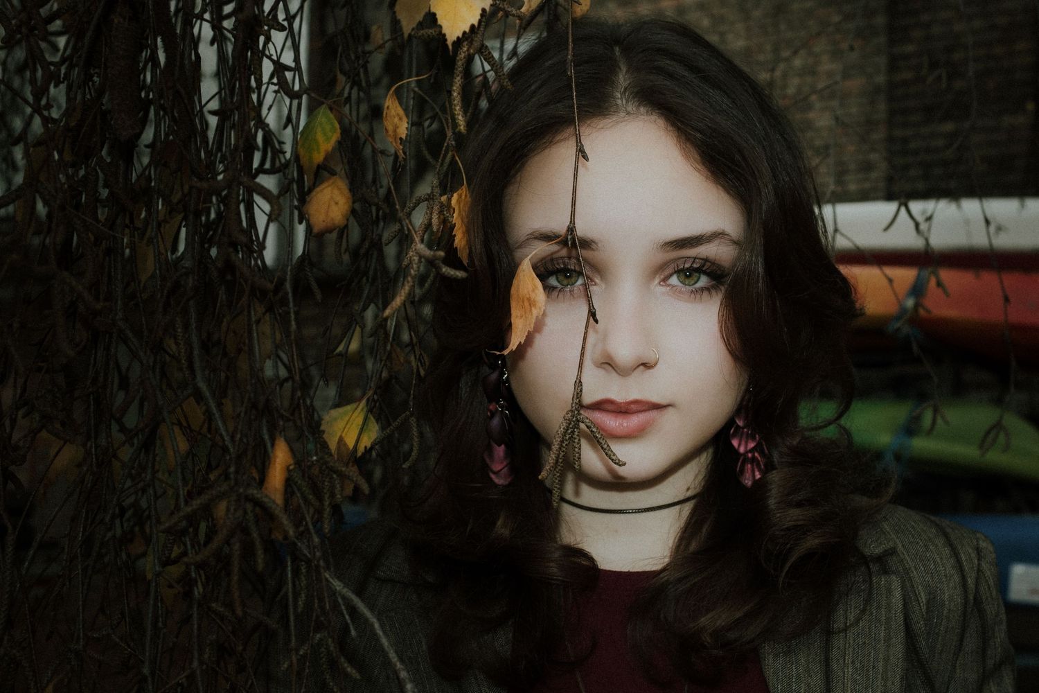 Atmospheric portrait series with autumn leaves and brick wall background.