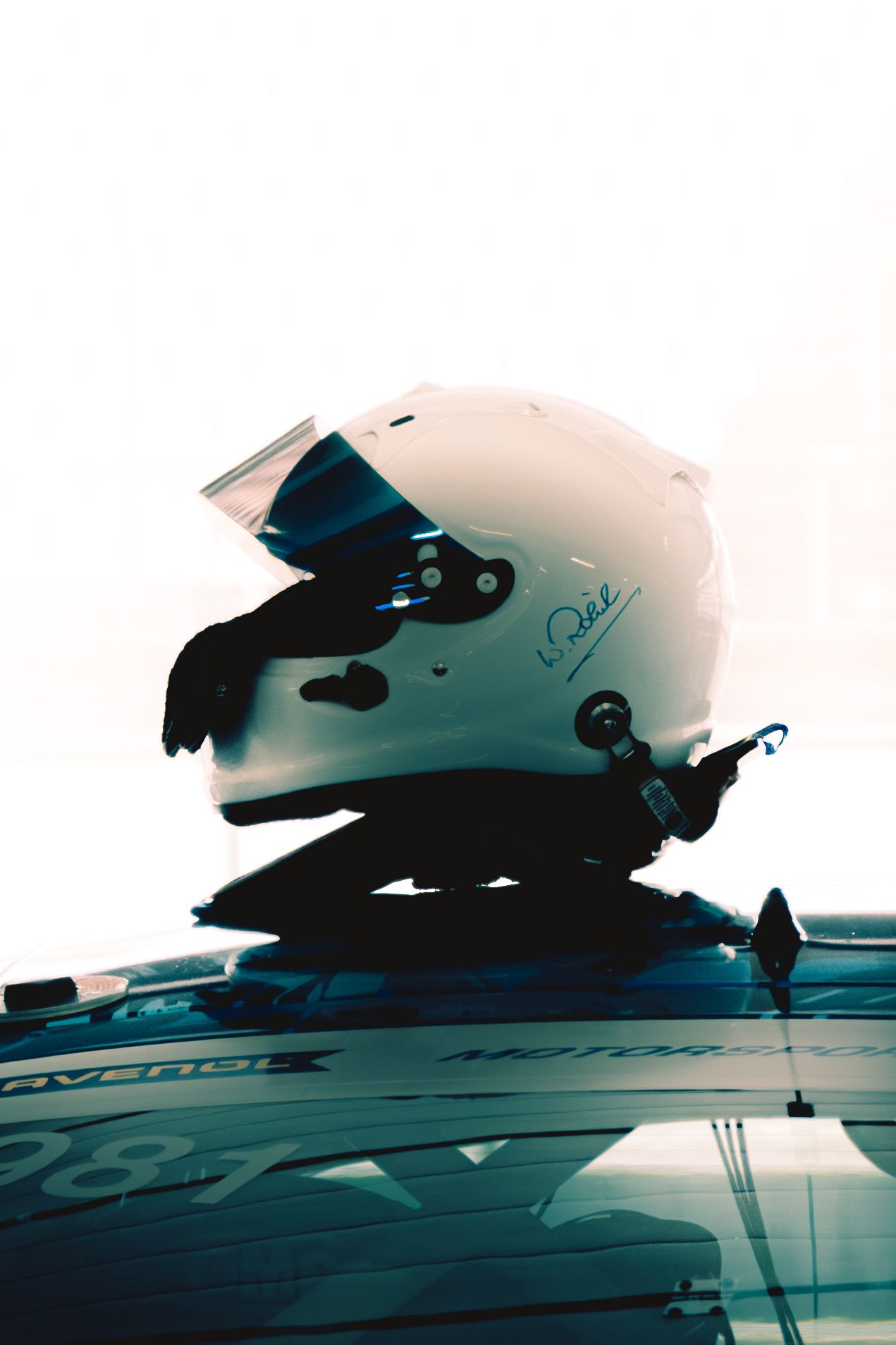 Abstract silhouettes of race cars reflected against a bright sky background.