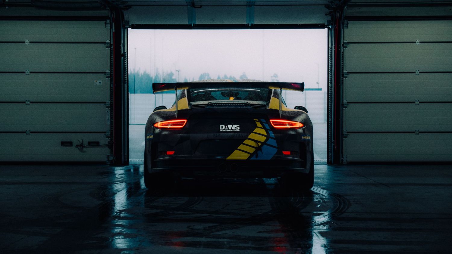Dark garage interior with silhouetted vehicles and dramatic lighting.