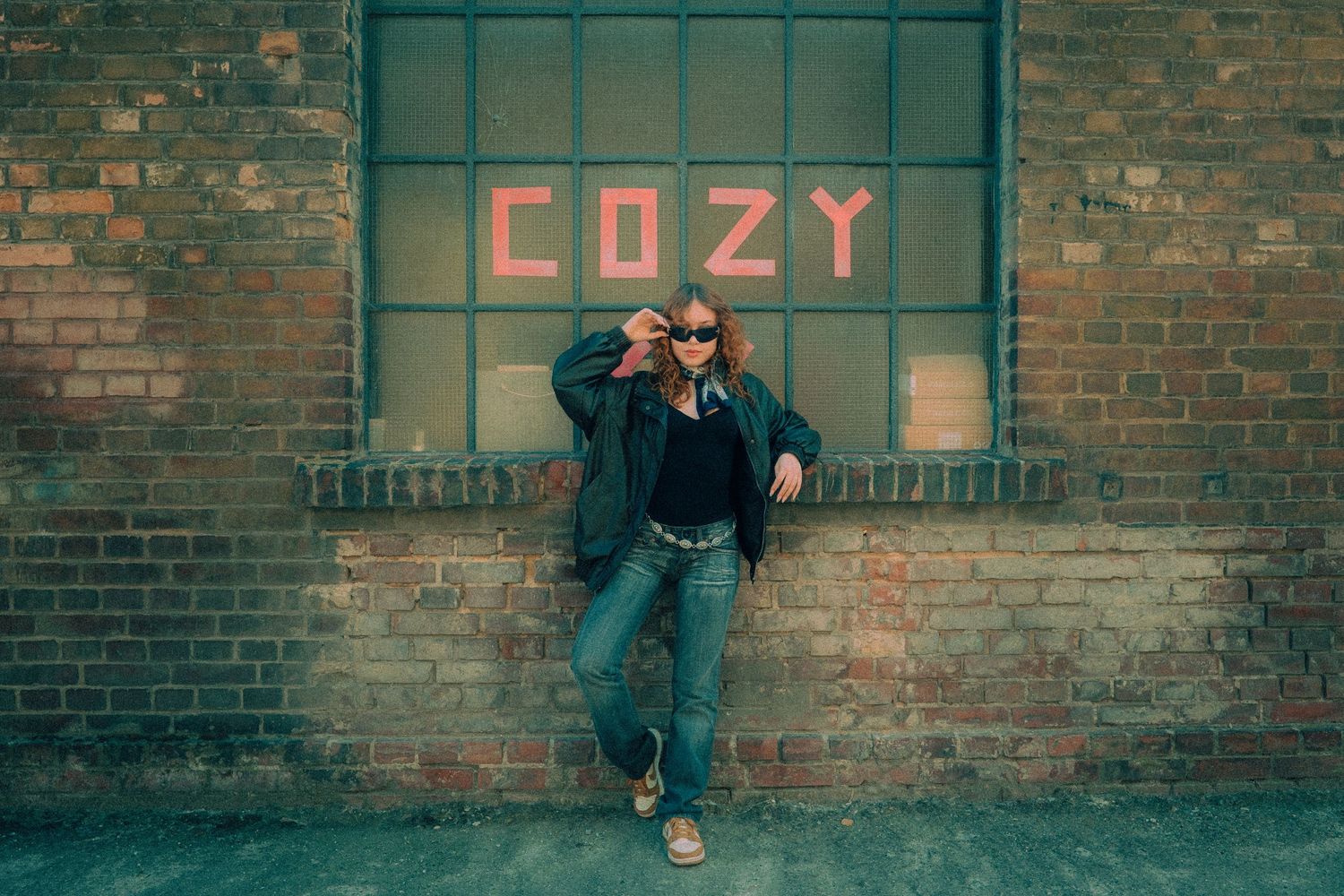 Panoramic view of brick wall with graffiti text reading 'LAZY' in urban setting.
