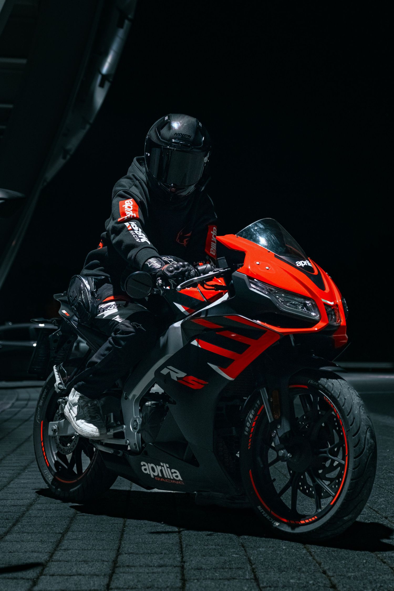 Red sport motorcycle dramatically lit against dark background showing sleek profile.