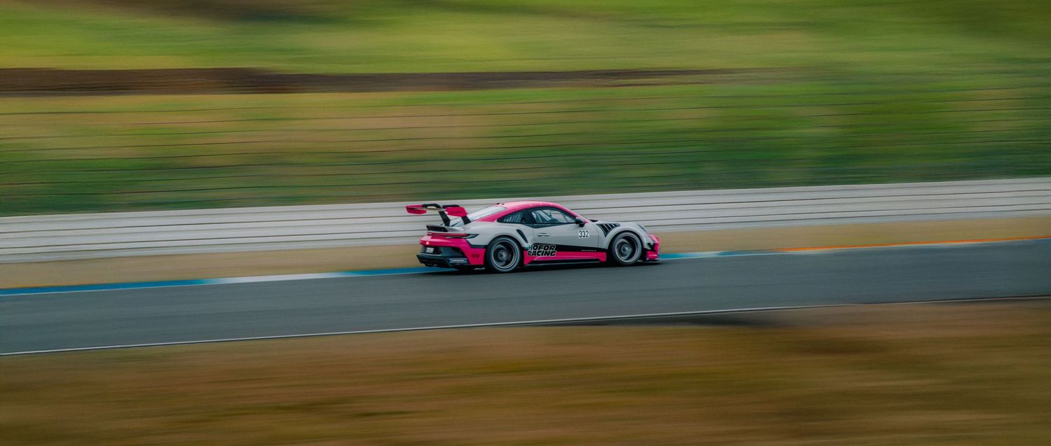 BMW race car creates dramatic motion blur while cornering on a sunny race day.