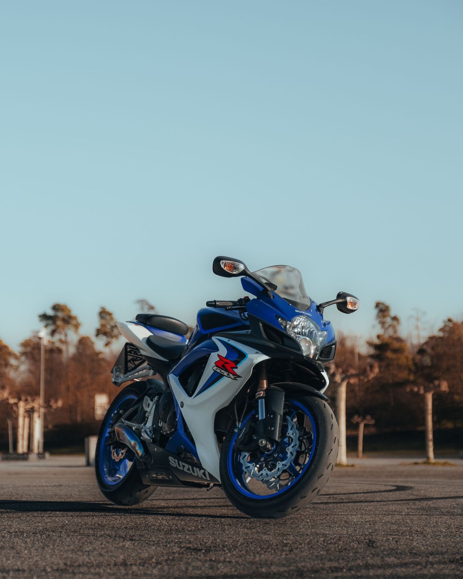 Blue and white sports motorcycle parked outdoors against a clear blue sky.