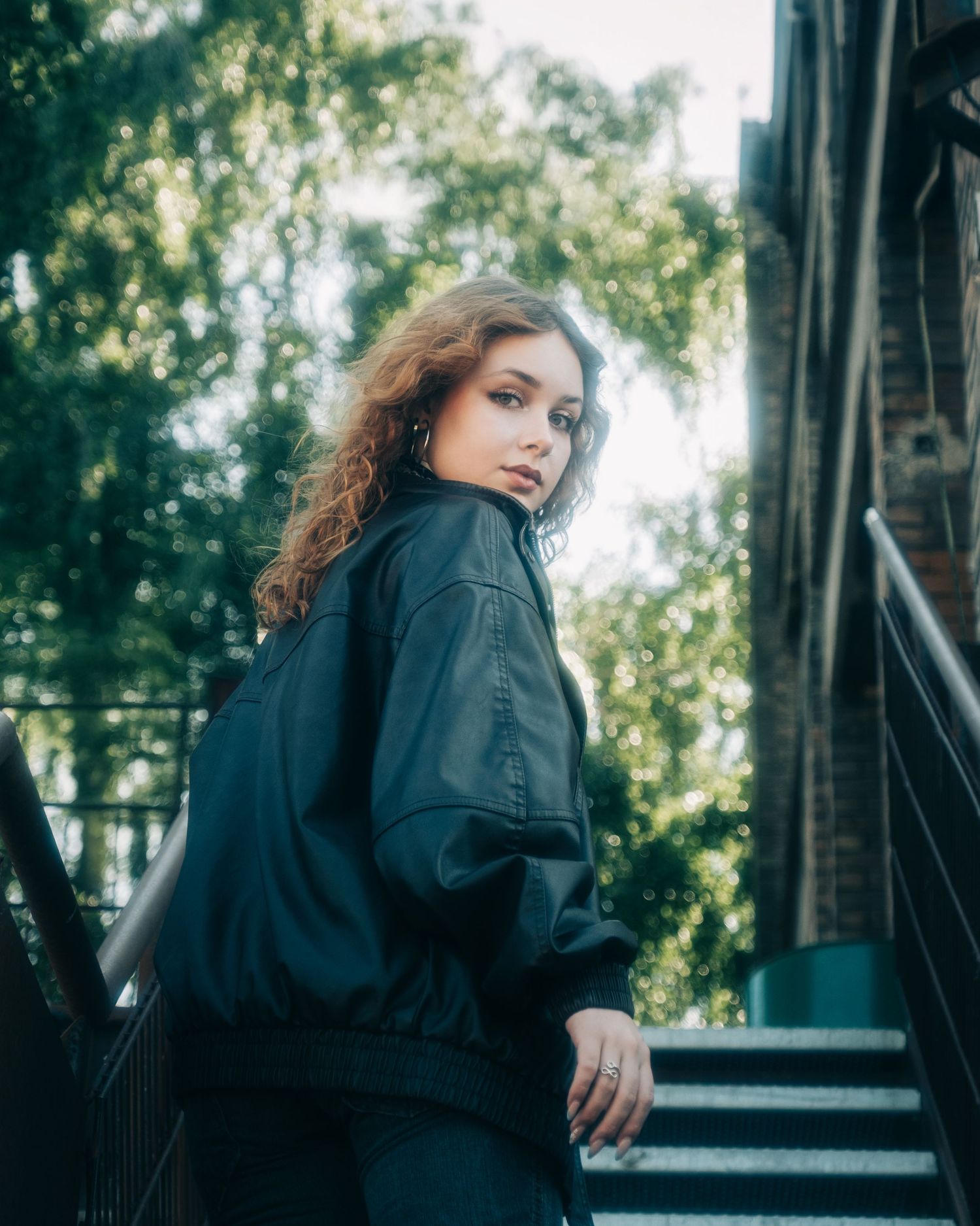 Fashion portrait series outdoors with natural lighting and leather jacket against brick building.