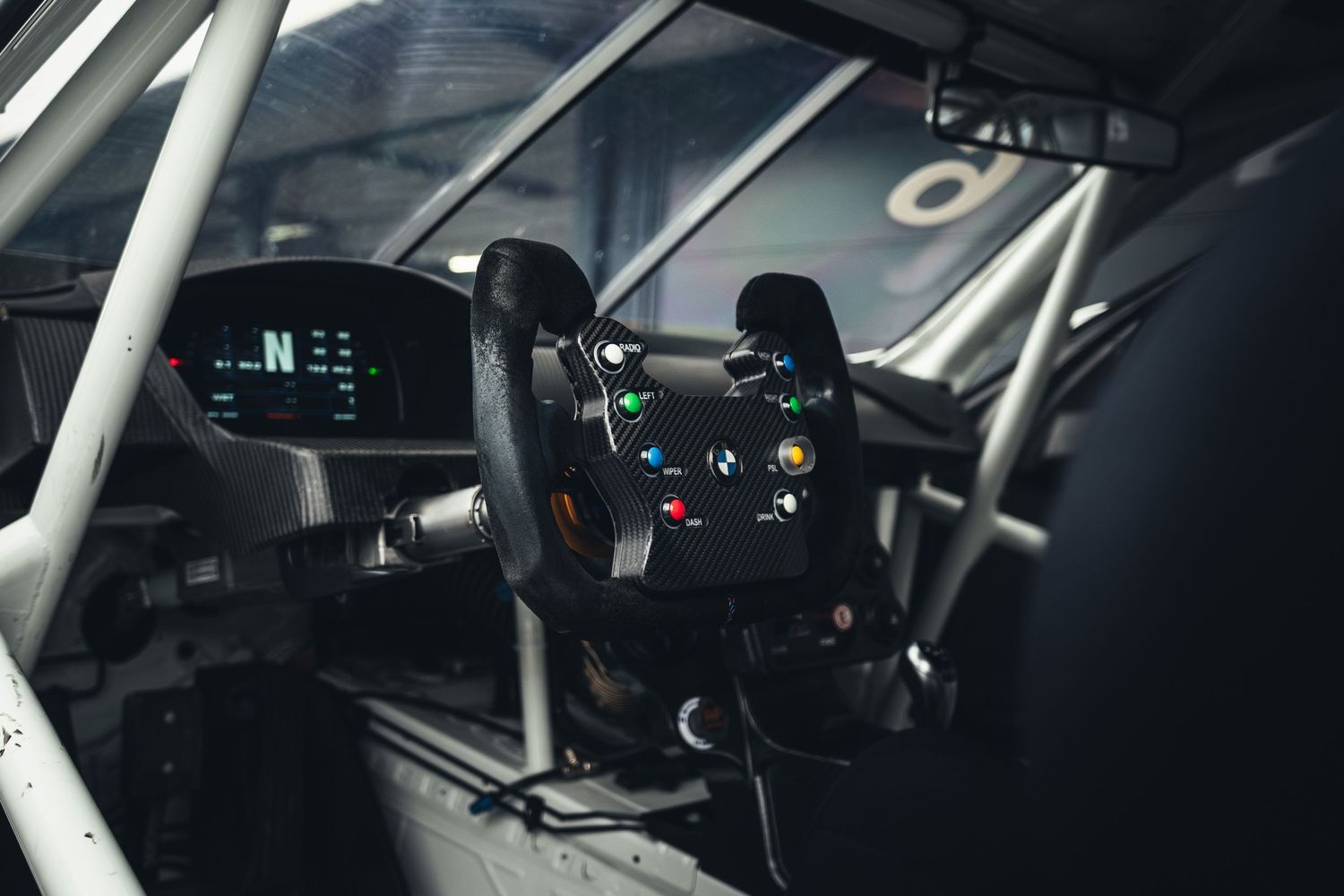 Interior view of BMW M4 GT3 race car showing racing steering wheel and digital dashboard.