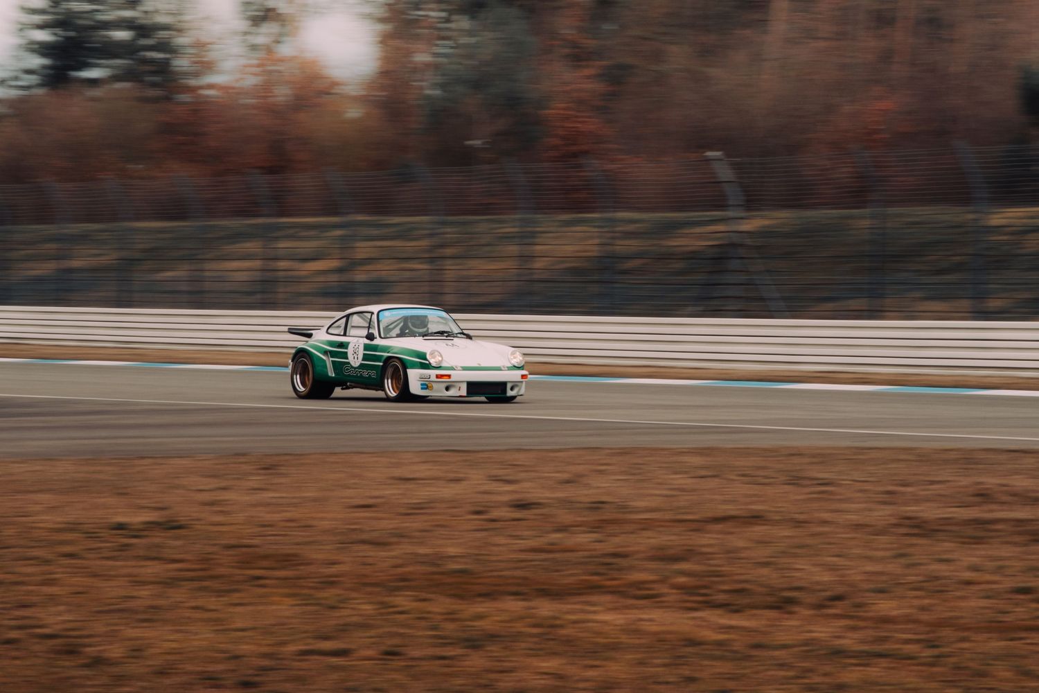 BMW race car speeds around a racetrack with motion blur effect at sunset.