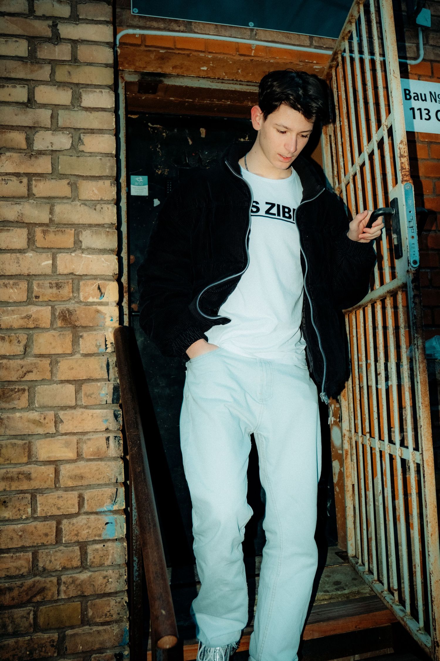 Figure in white clothing moving through a brick-lined corridor or basement area.