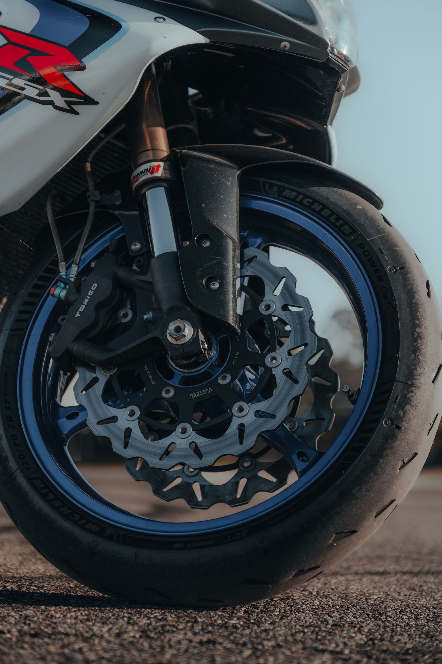 Close-up of motorcycle front wheel brake system with blue accent details.