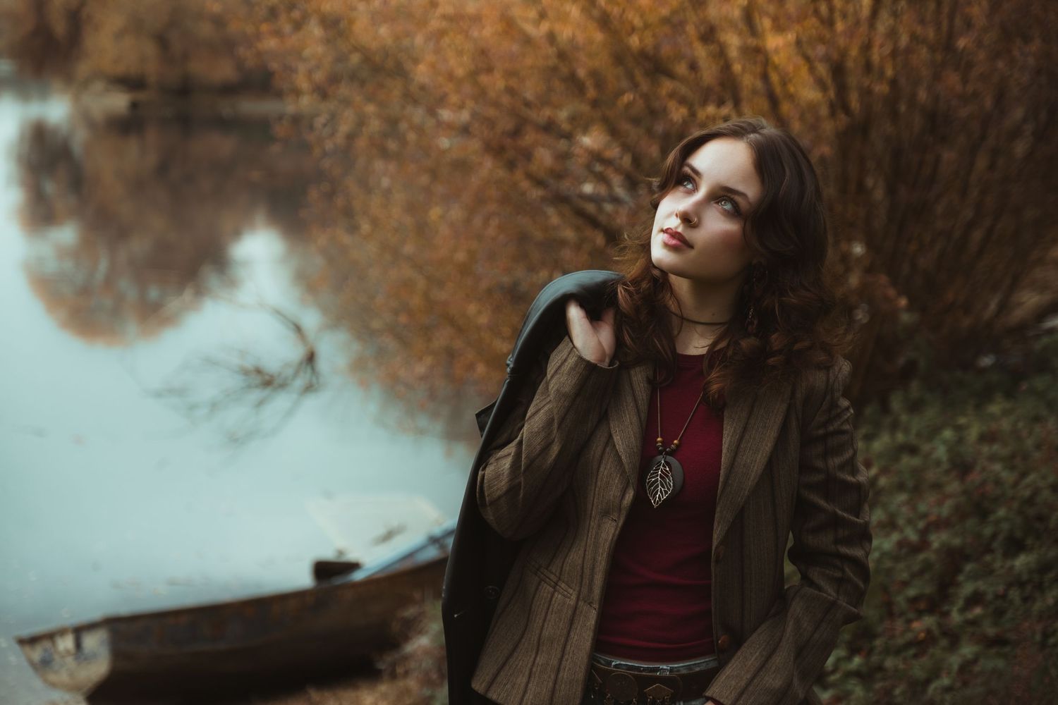 Atmospheric autumn portrait of someone in a brown coat by a misty lake.