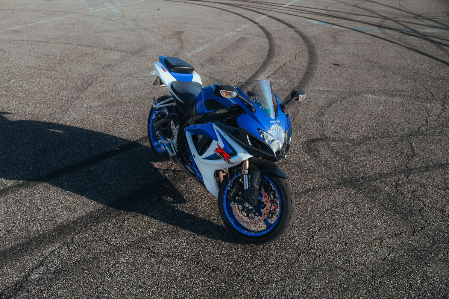 Sport bike on asphalt with tire marks visible in dramatic lighting.