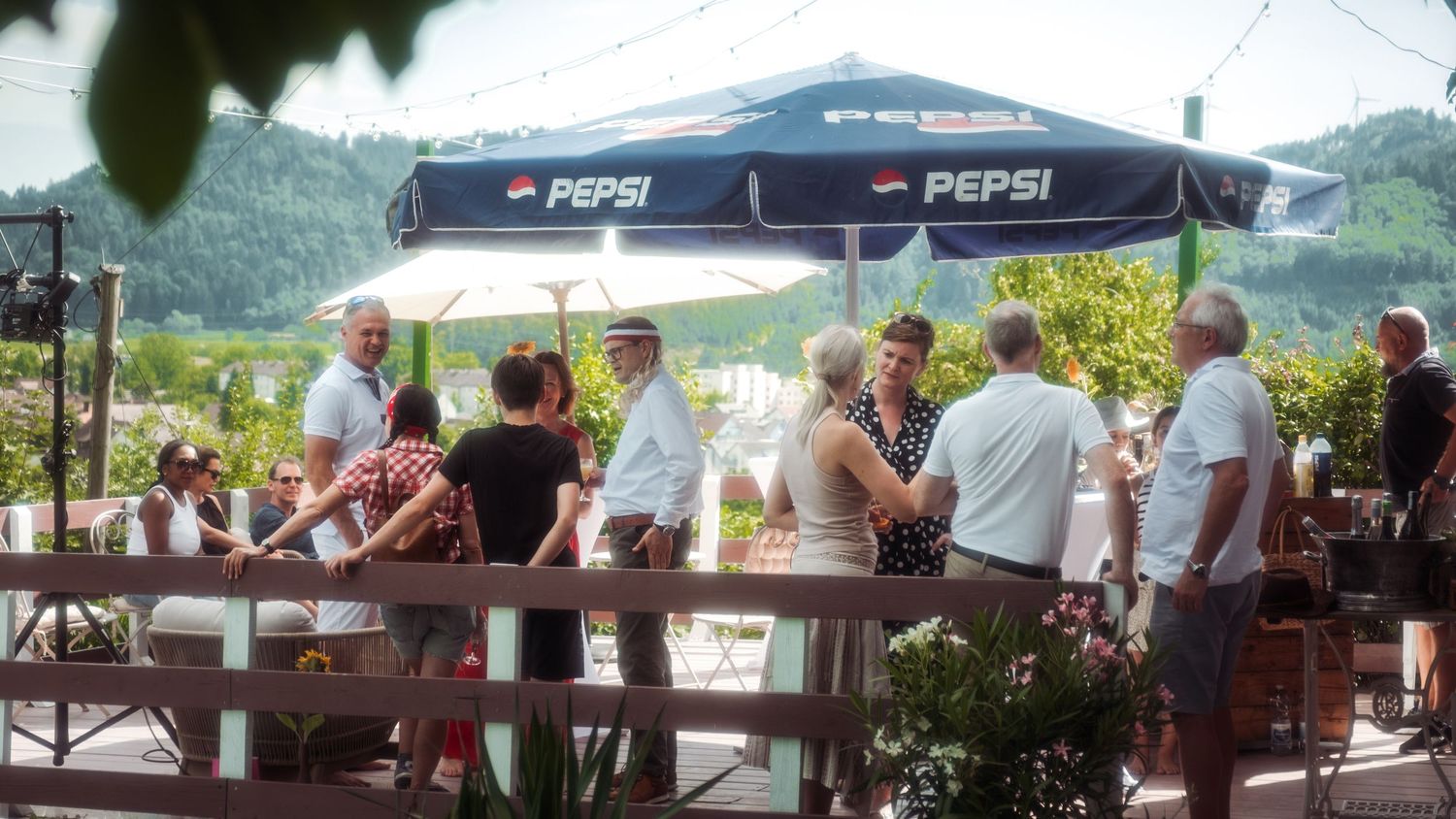 Outdoor gathering area with picnic tables and Pepsi umbrellas on sunny day.