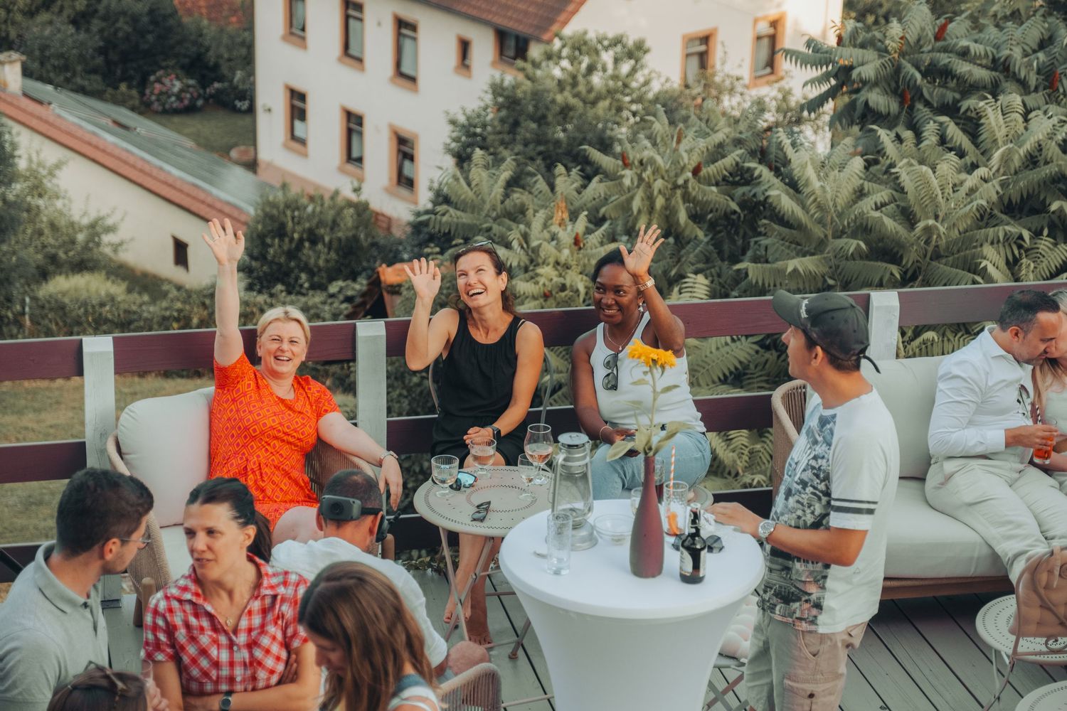 Social gathering on an outdoor patio with string lights and umbrellas.