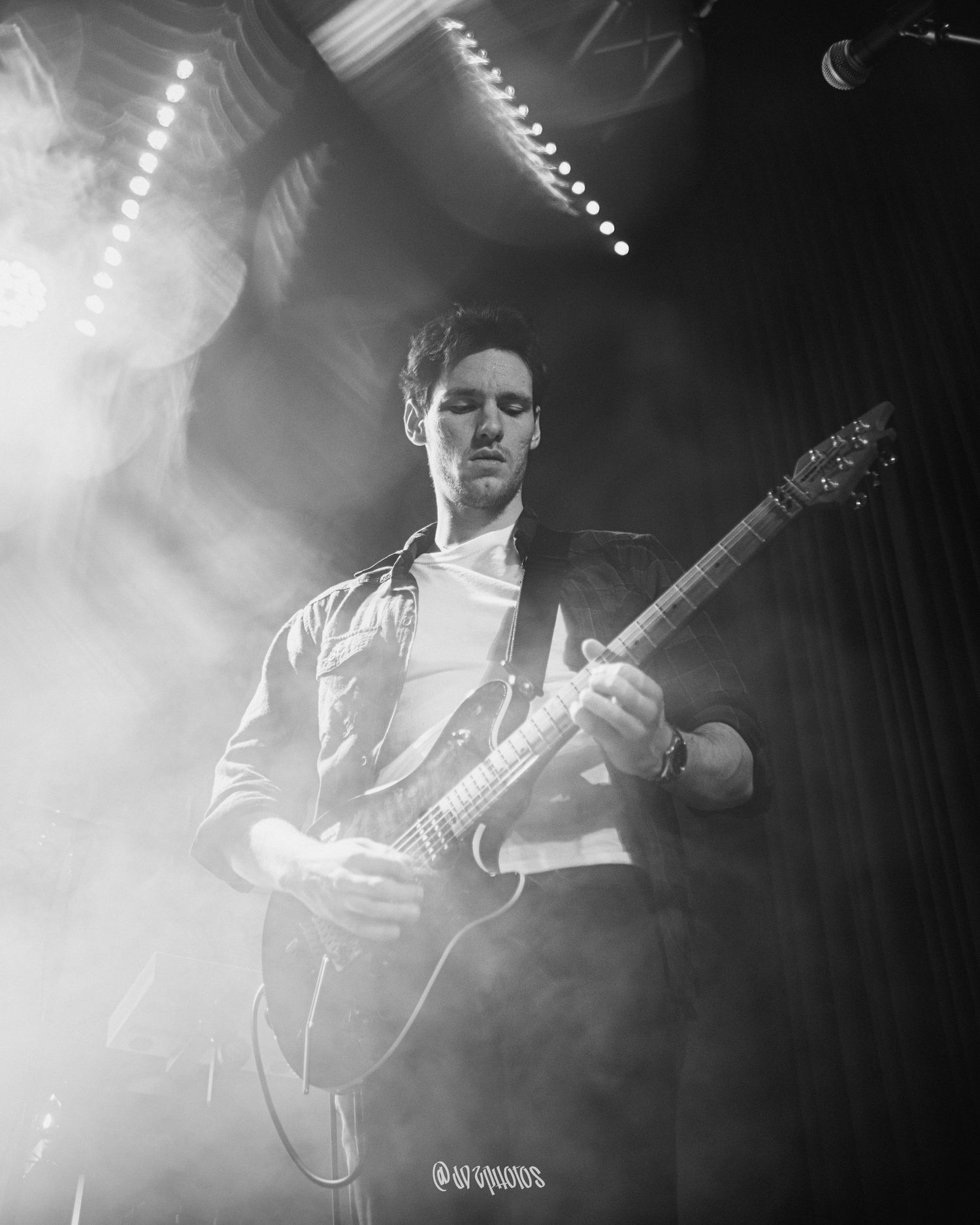 Musicians performing on stage in atmospheric black and white photography.